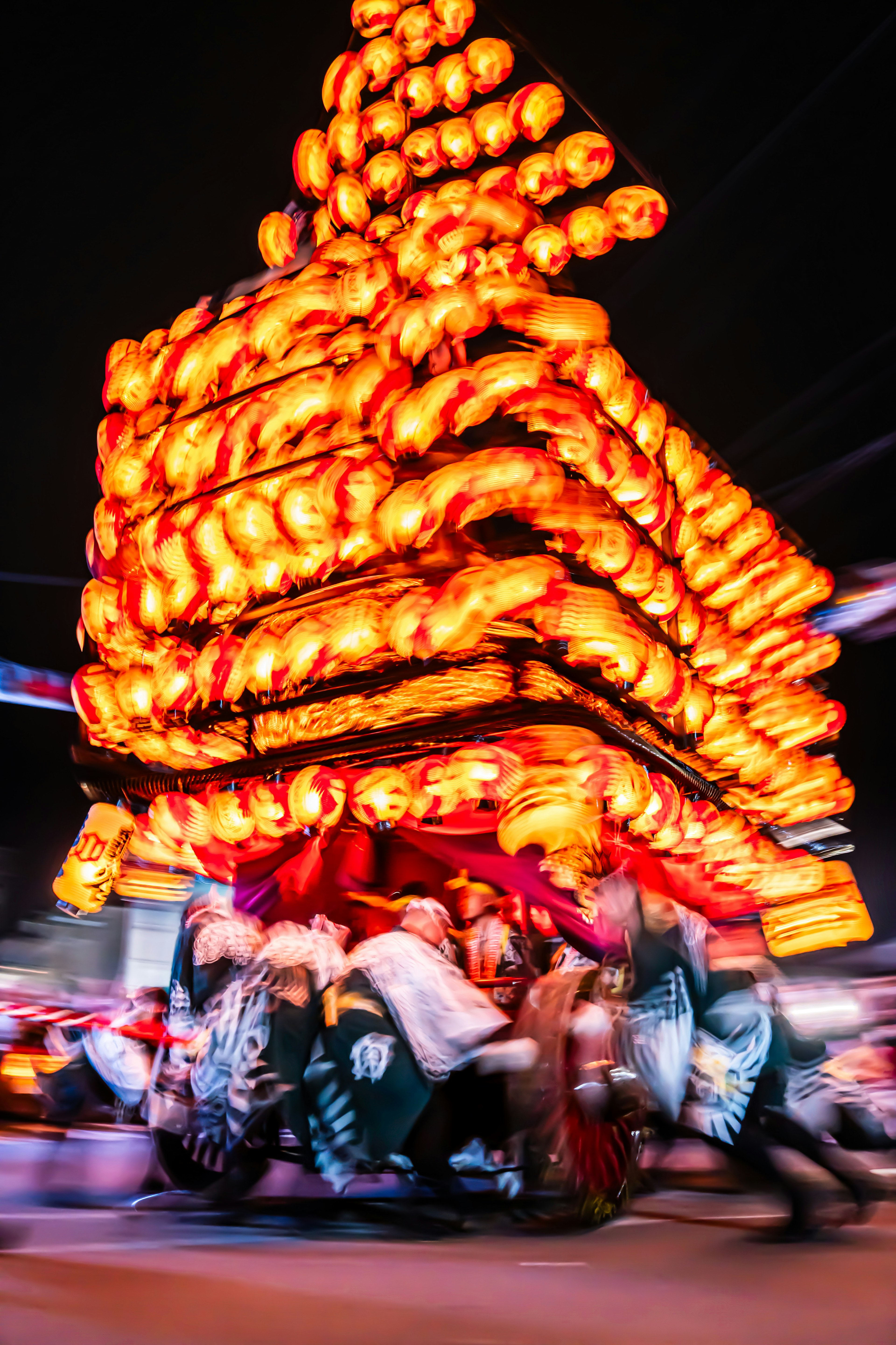 A festival float adorned with glowing lanterns in motion during the night