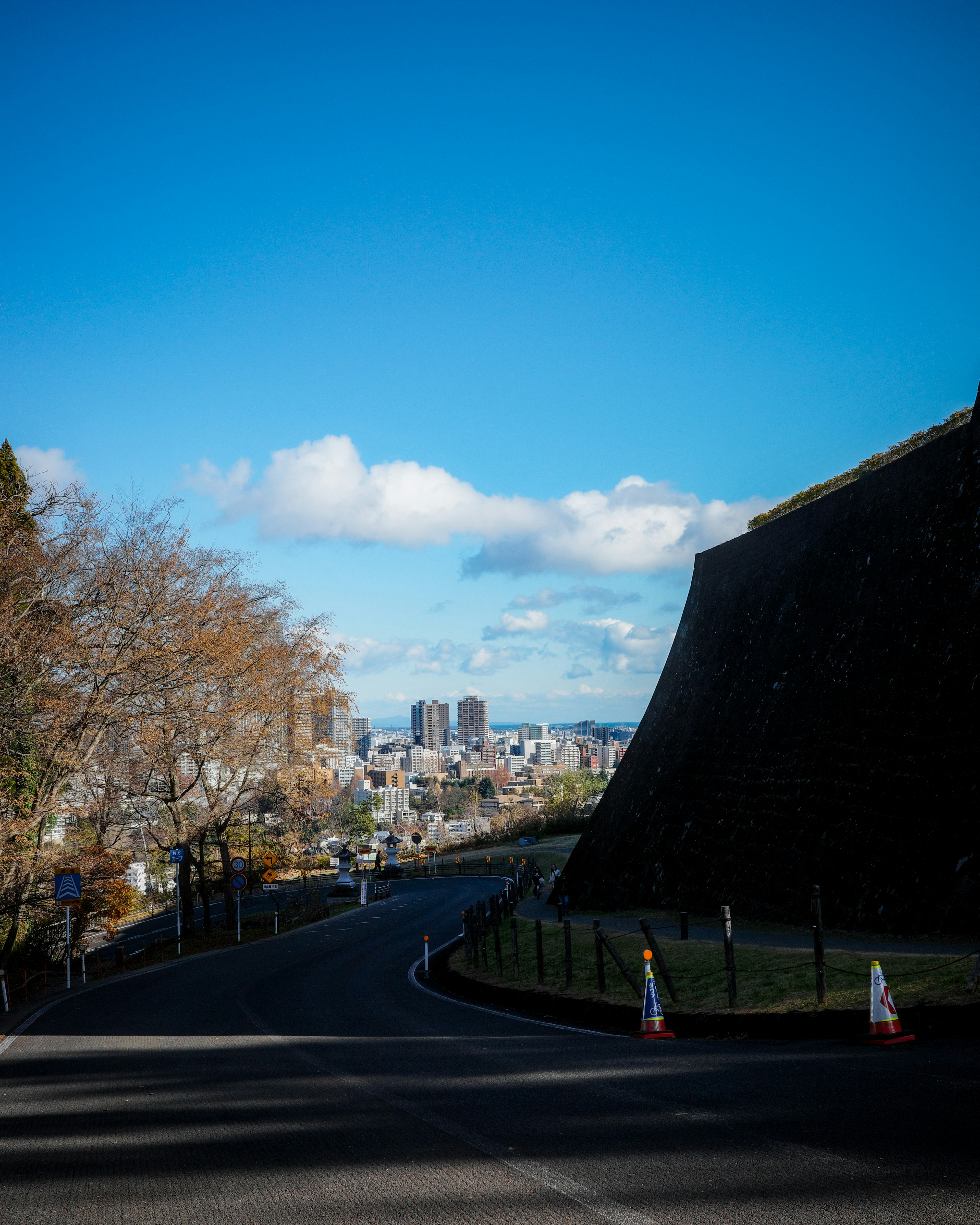 青空の下、曲がりくねった道路と城壁が見える風景