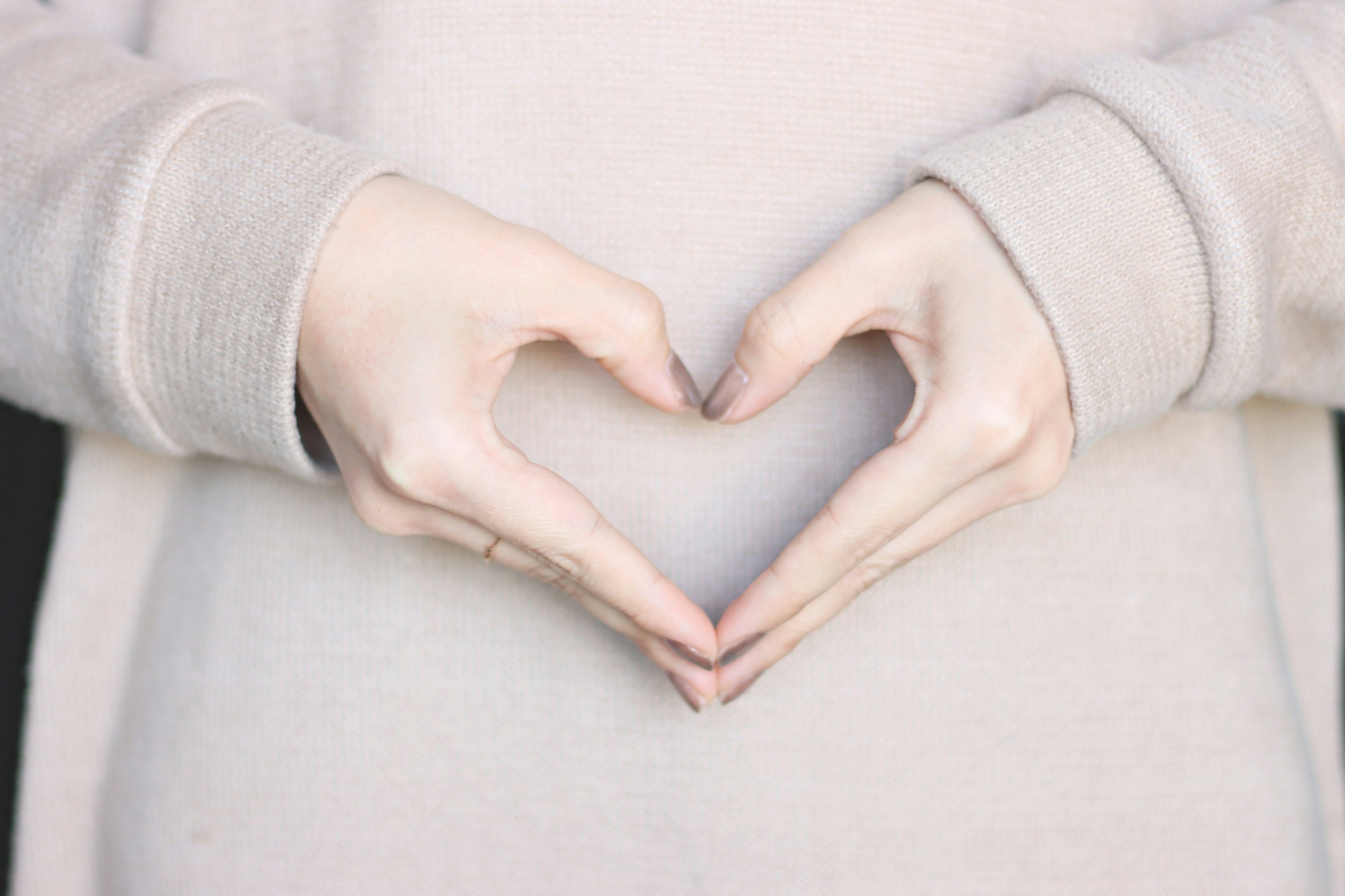 Hands forming a heart shape with a soft sweater