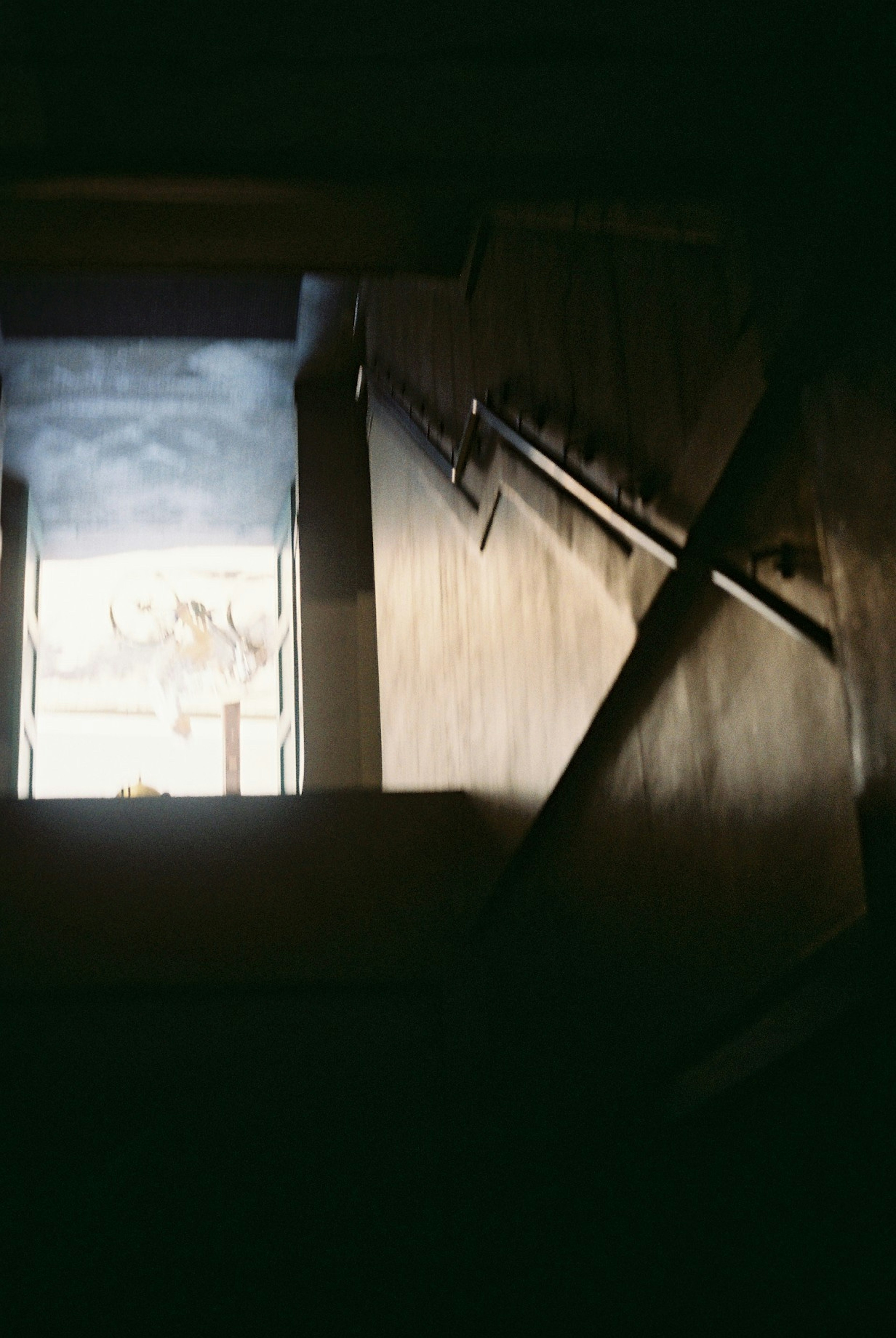 A view from a dark staircase towards an open door with light coming through