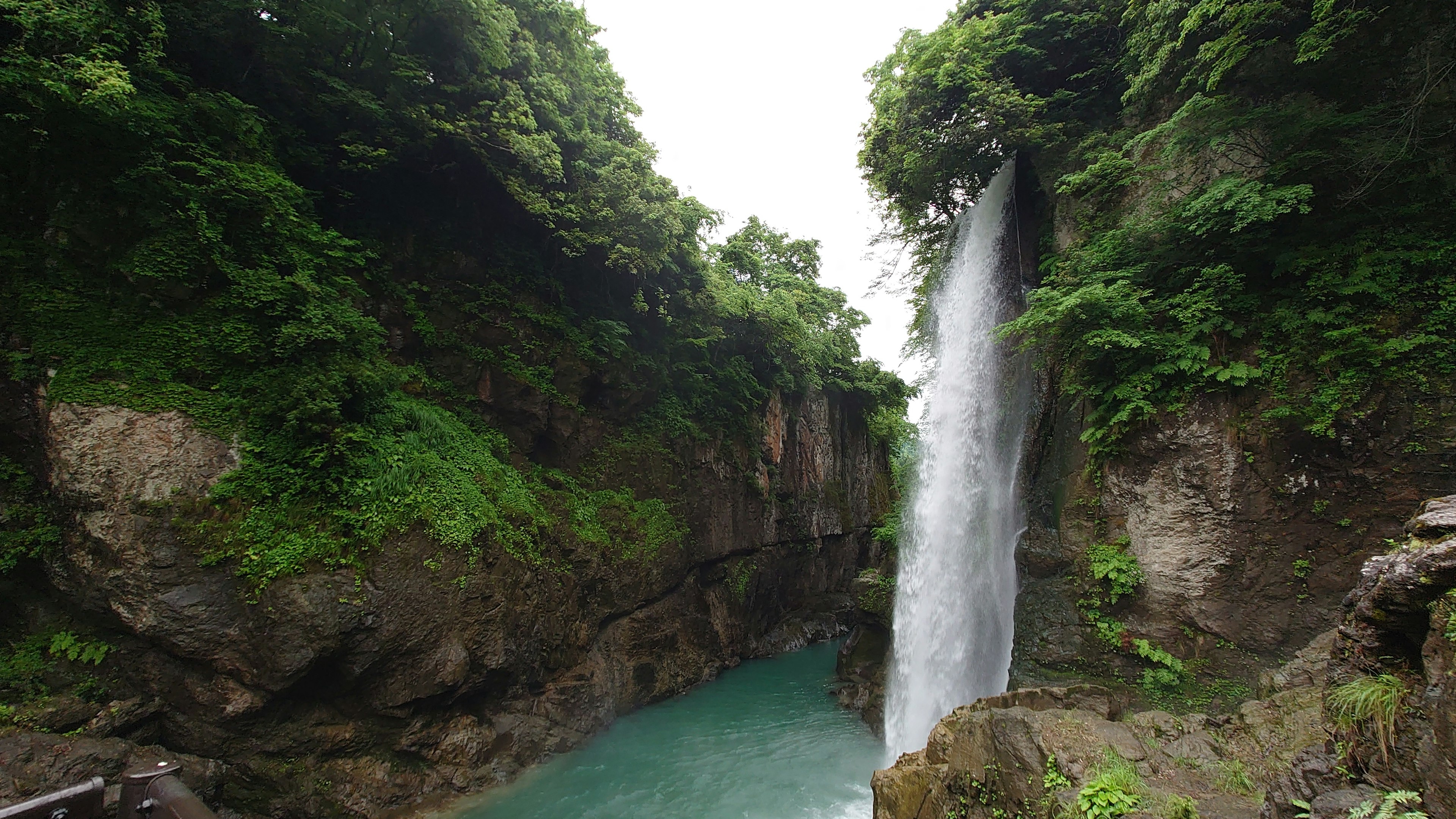 Schöner Wasserfall umgeben von Grün mit einem türkisfarbenen Pool