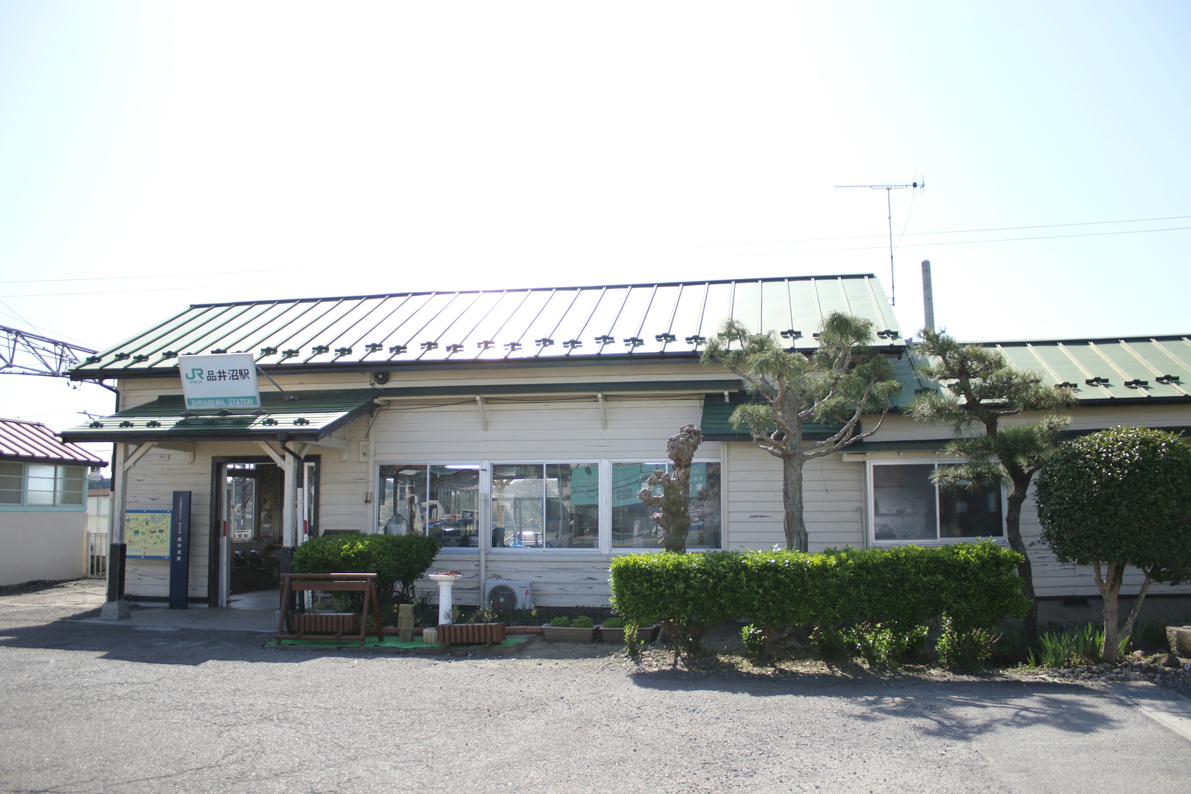 緑の屋根を持つ小さな建物と植えられた低木がある風景