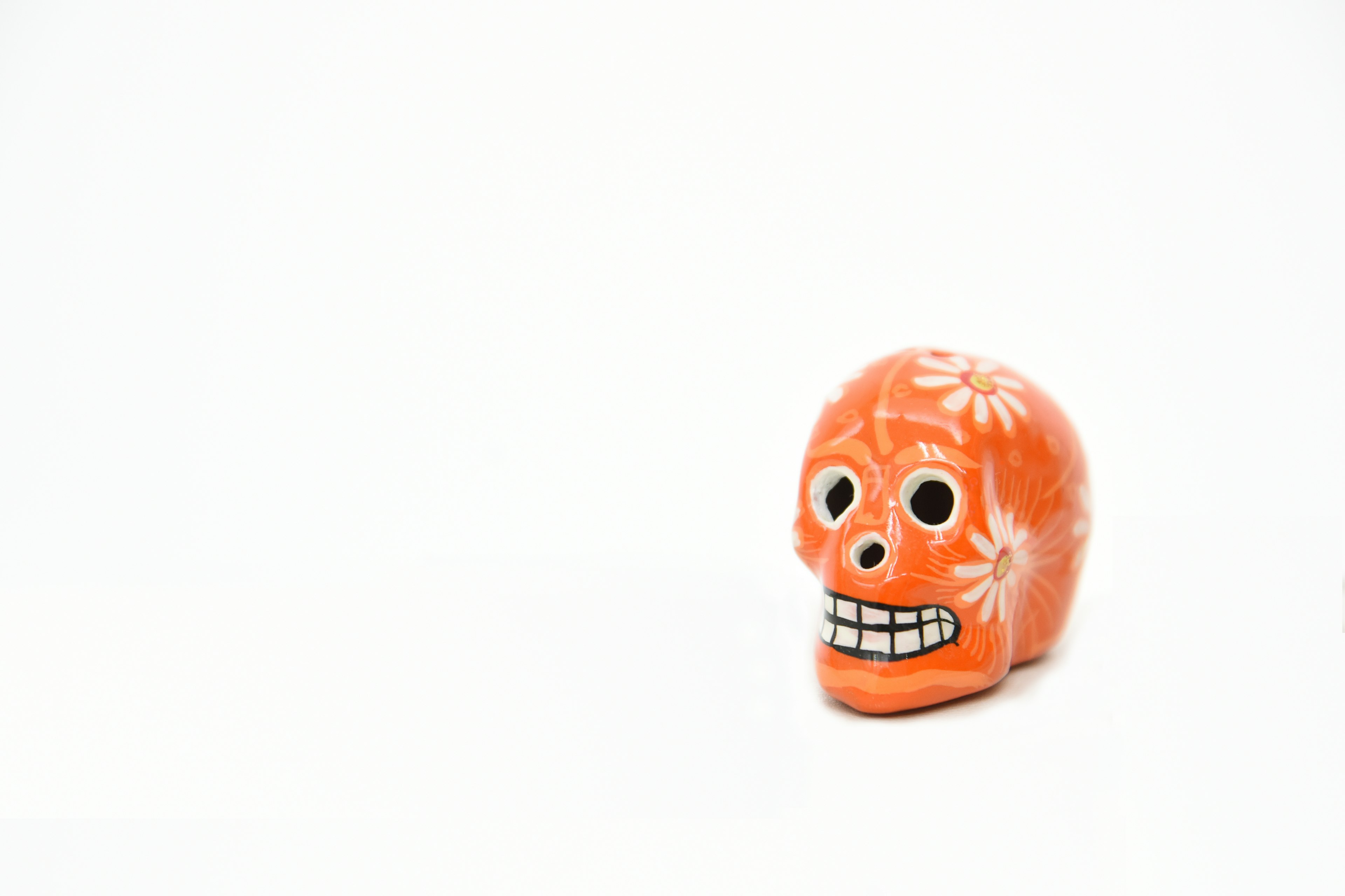 Figurita de calavera naranja decorativa con patrones florales