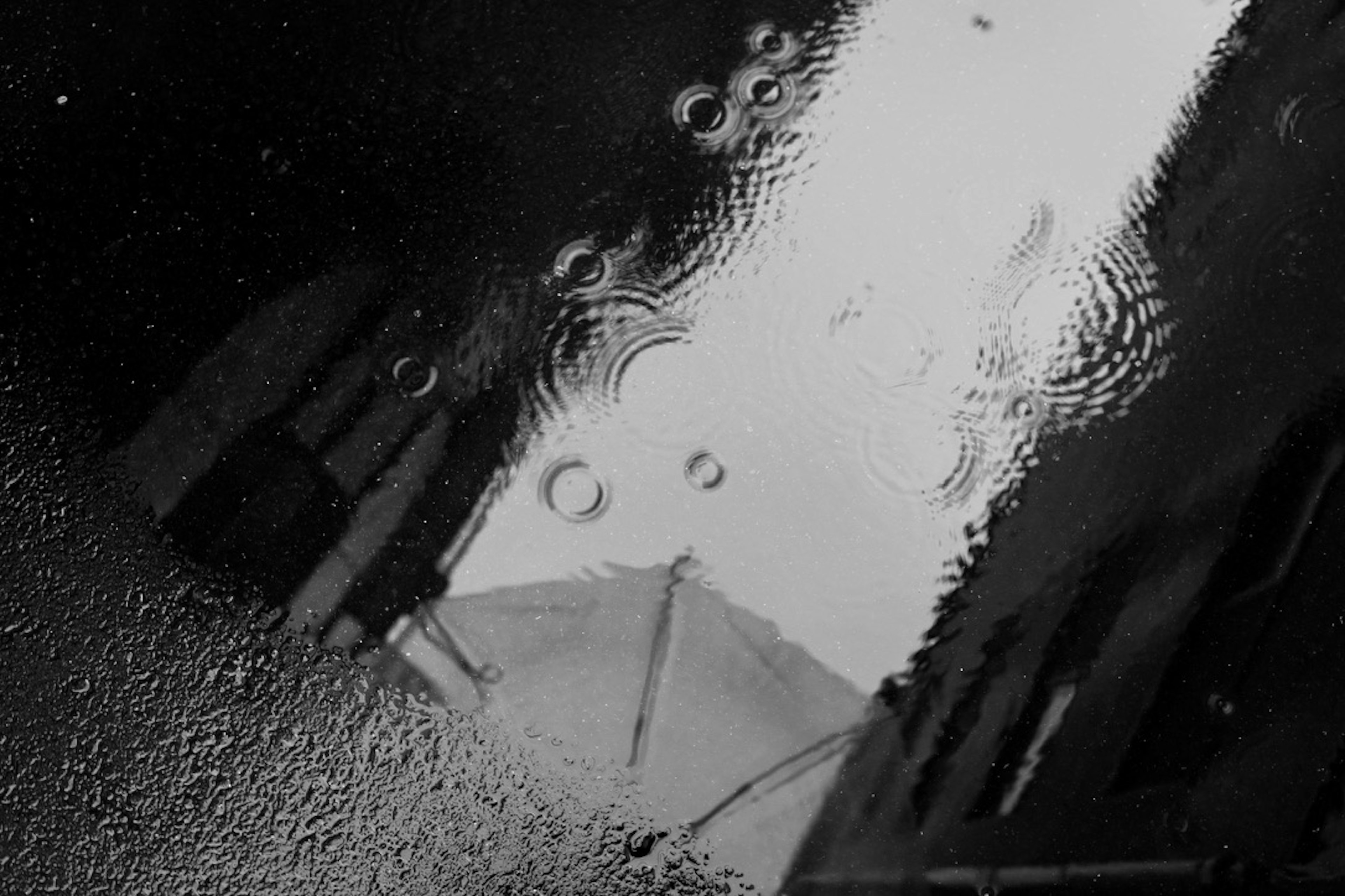 Reflection of an umbrella and buildings in a rain puddle