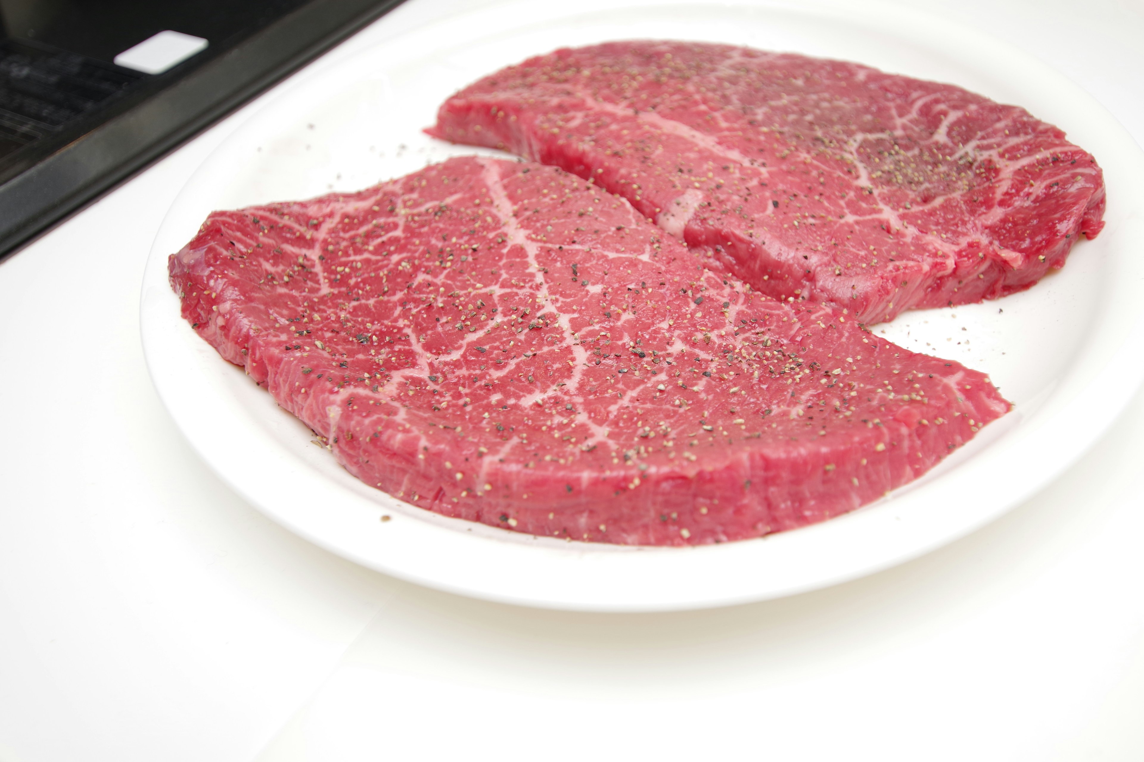 Deux morceaux de steaks de viande rouge sur une assiette blanche