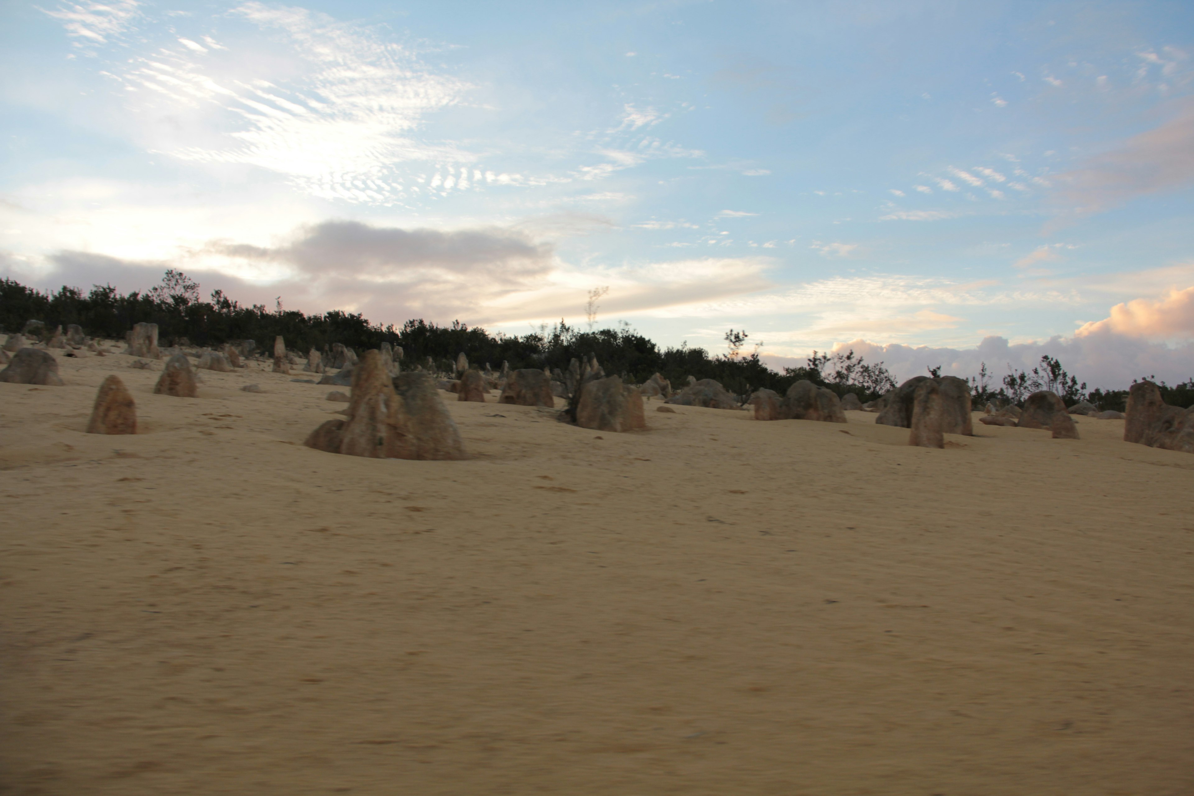 Pilares de piedra dispersos en dunas de arena bajo un cielo azul