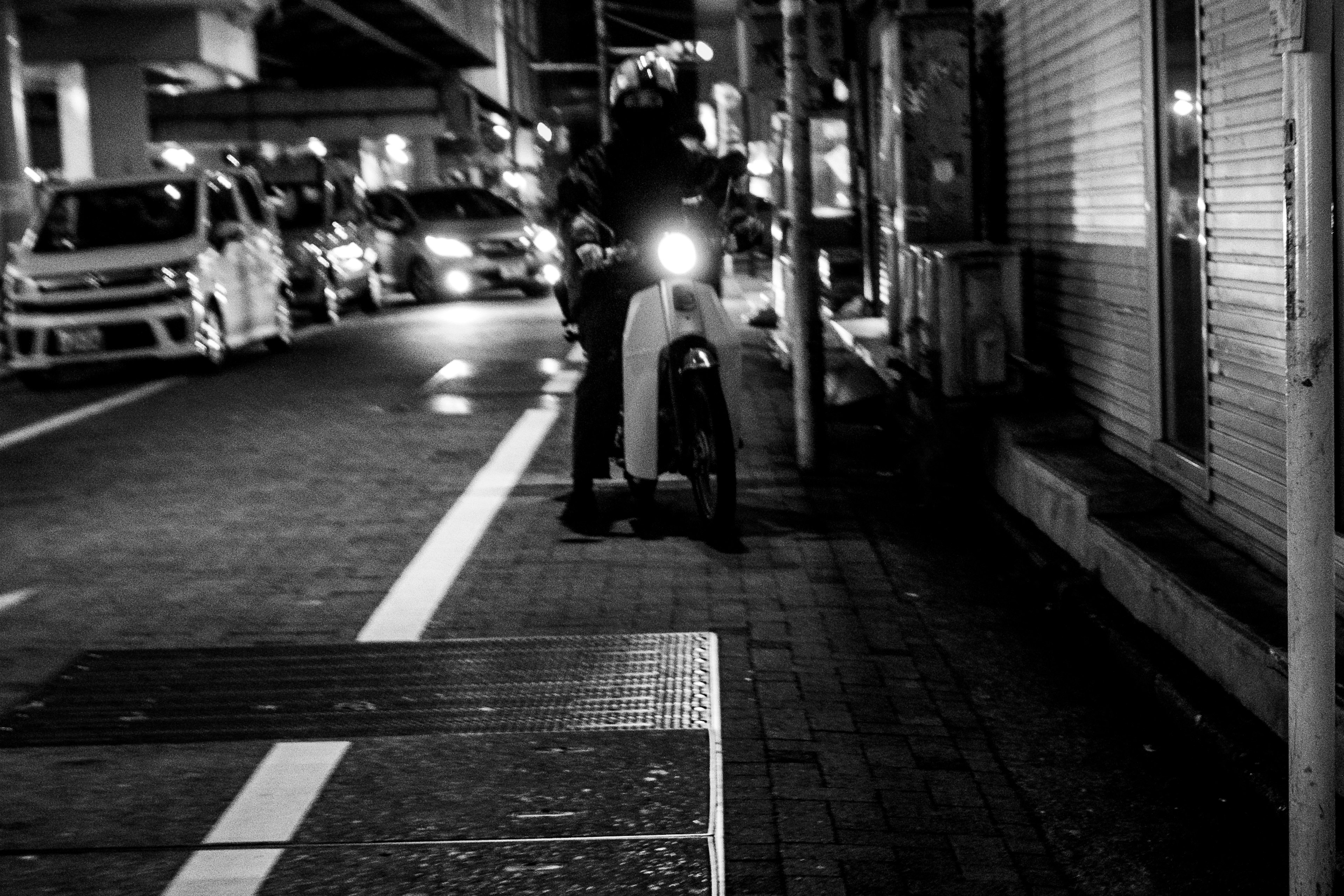 Moto parcheggiata in una strada cittadina di notte con una fila di auto