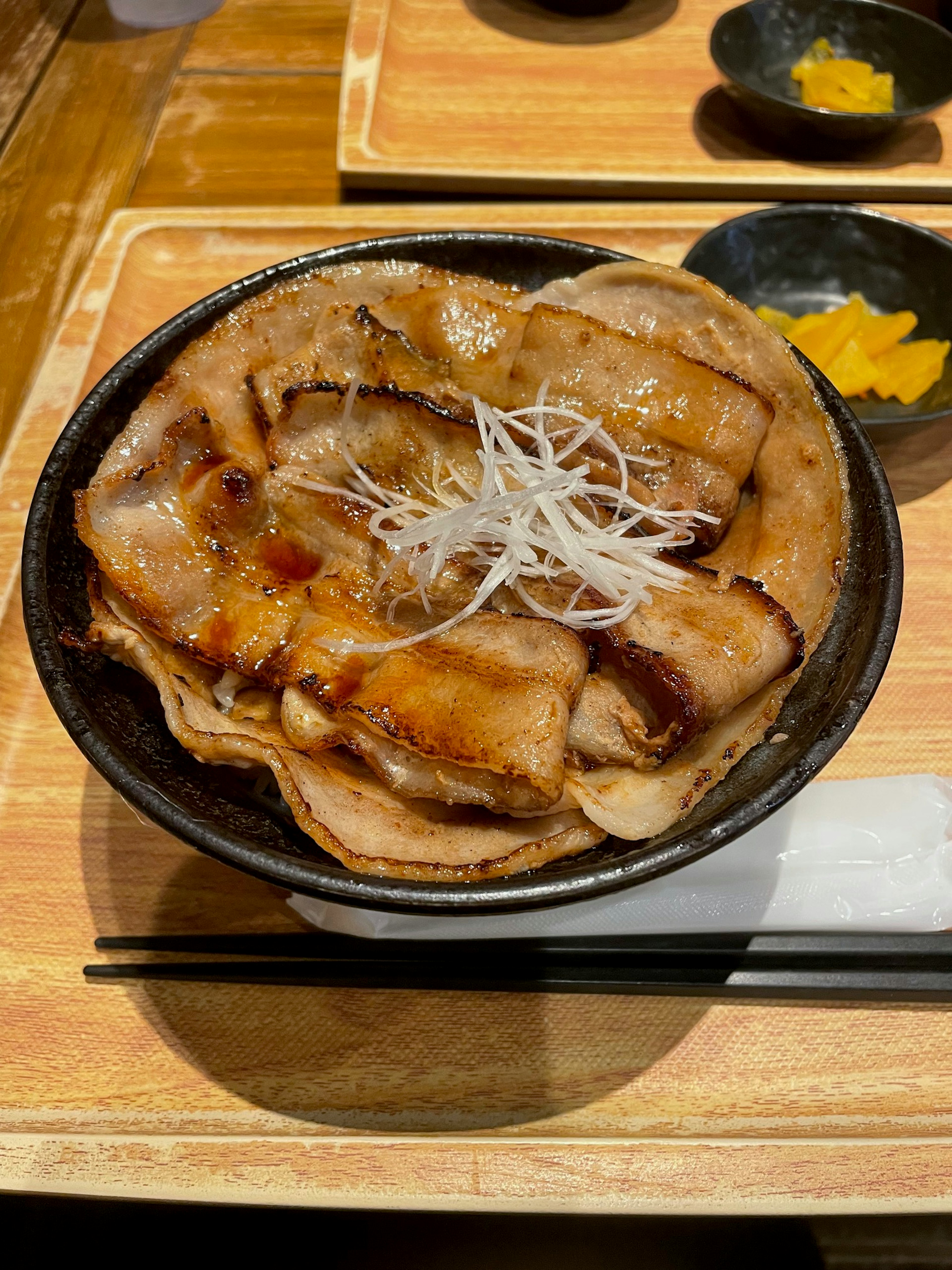 Bowl of grilled pork topped with shredded white onion