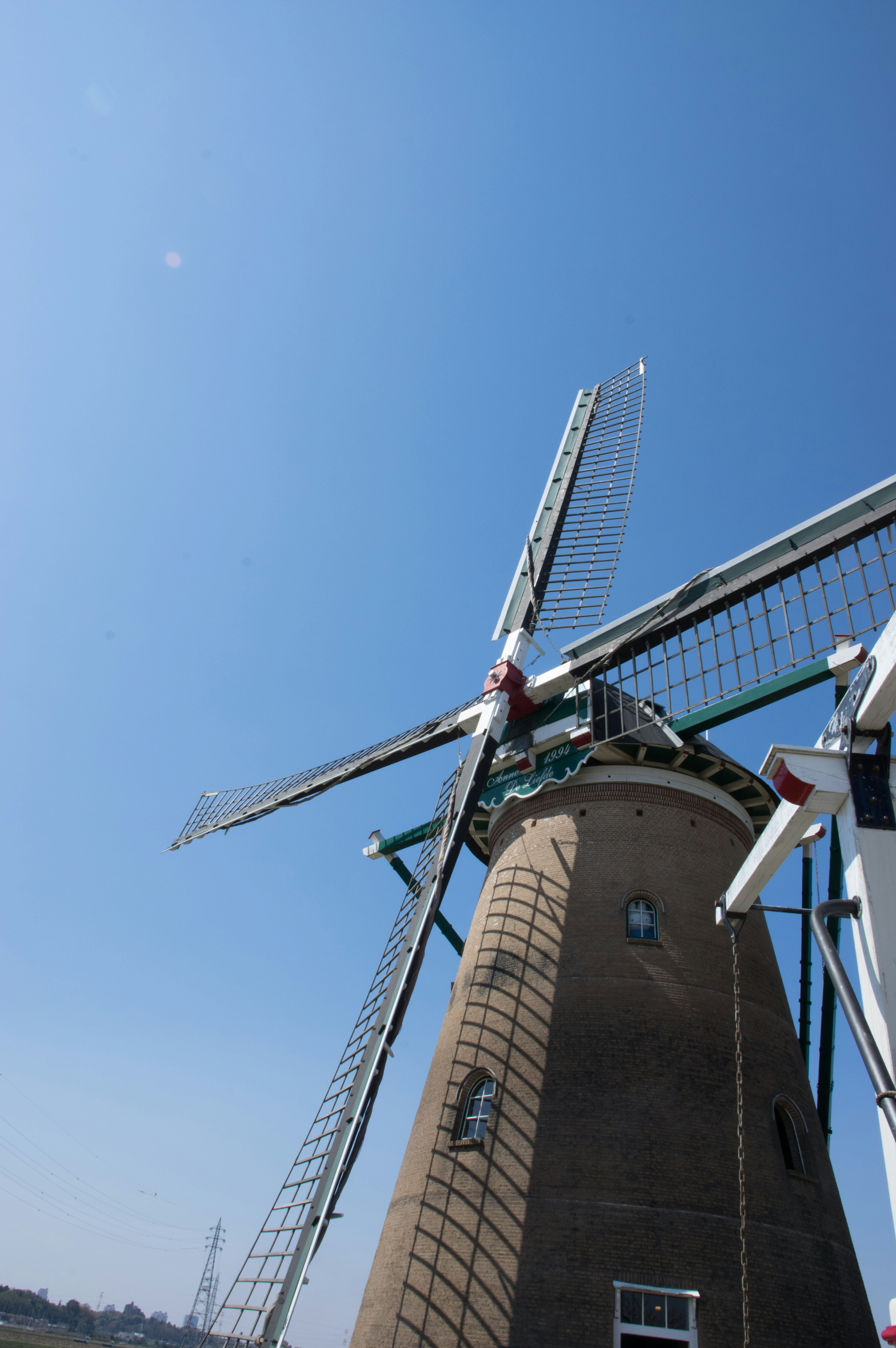 Vue latérale d'un moulin à vent avec des pales rotatives sous un ciel bleu