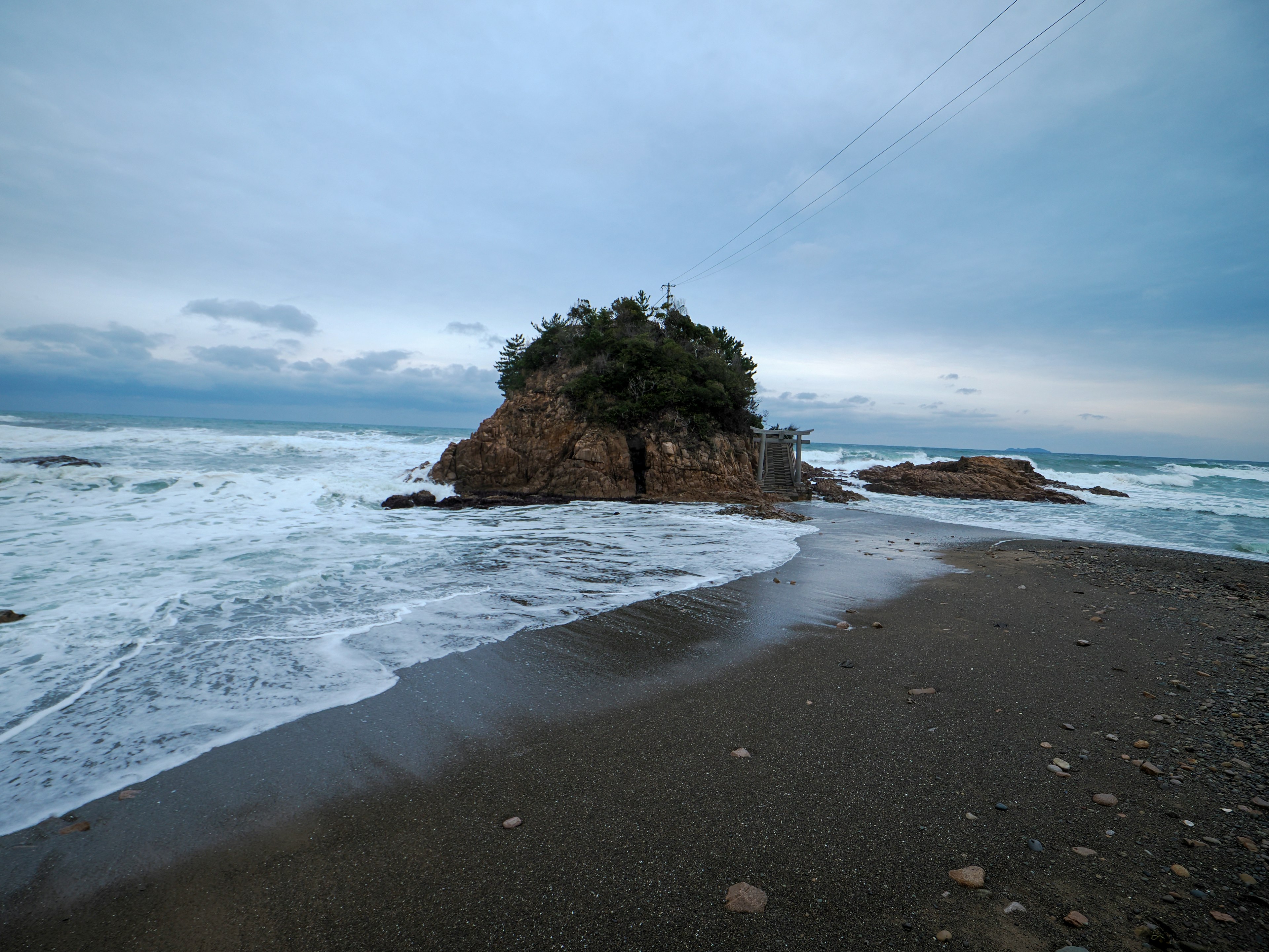 Vista escénica de una playa de arena con olas y una pequeña isla