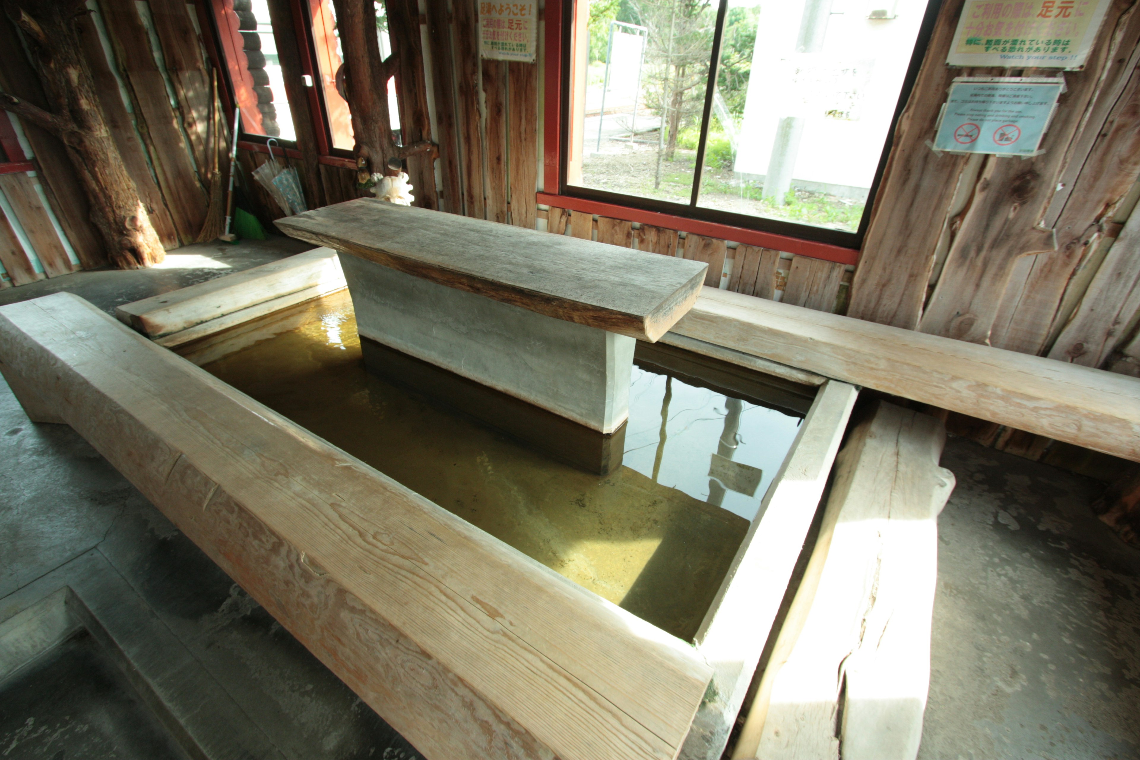 Intérieur avec une table en bois et des bancs autour d'un bassin rempli d'eau