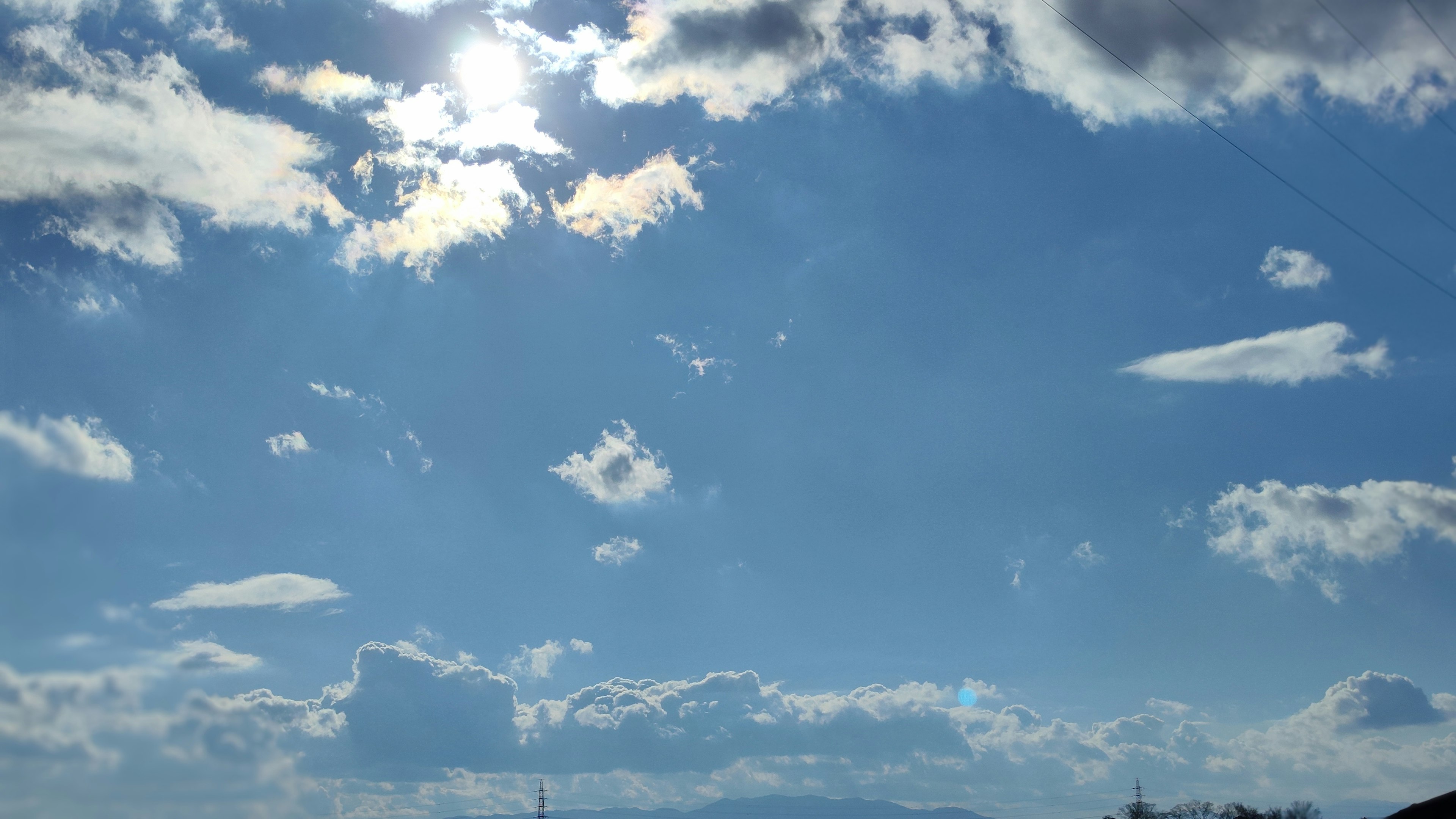 A blue sky with white clouds and sunlight