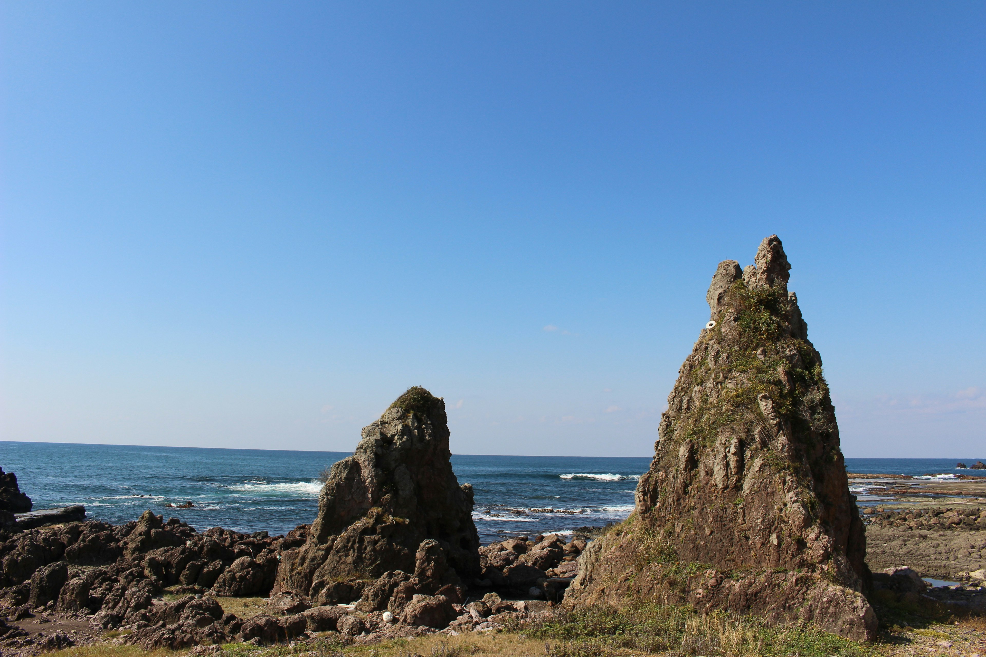 Vista panoramica di formazioni rocciose vicino all'oceano sotto un cielo blu chiaro