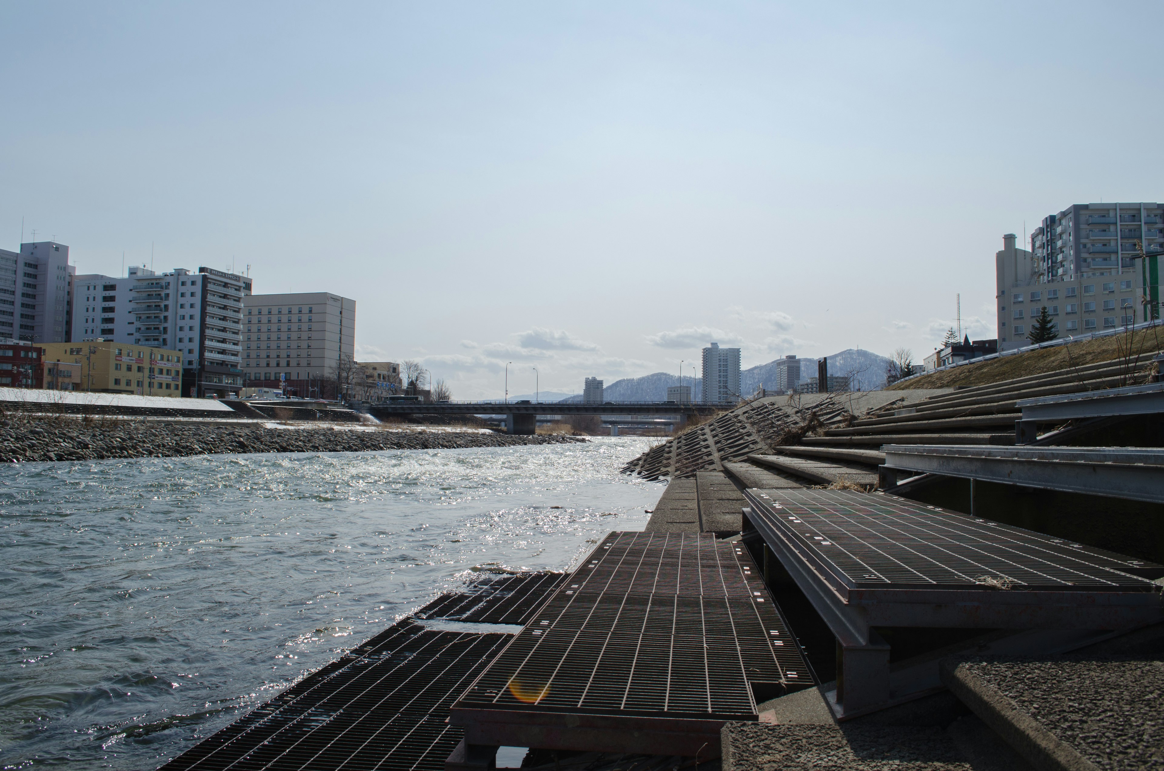 Scenic view of a calm river with modern buildings in the background