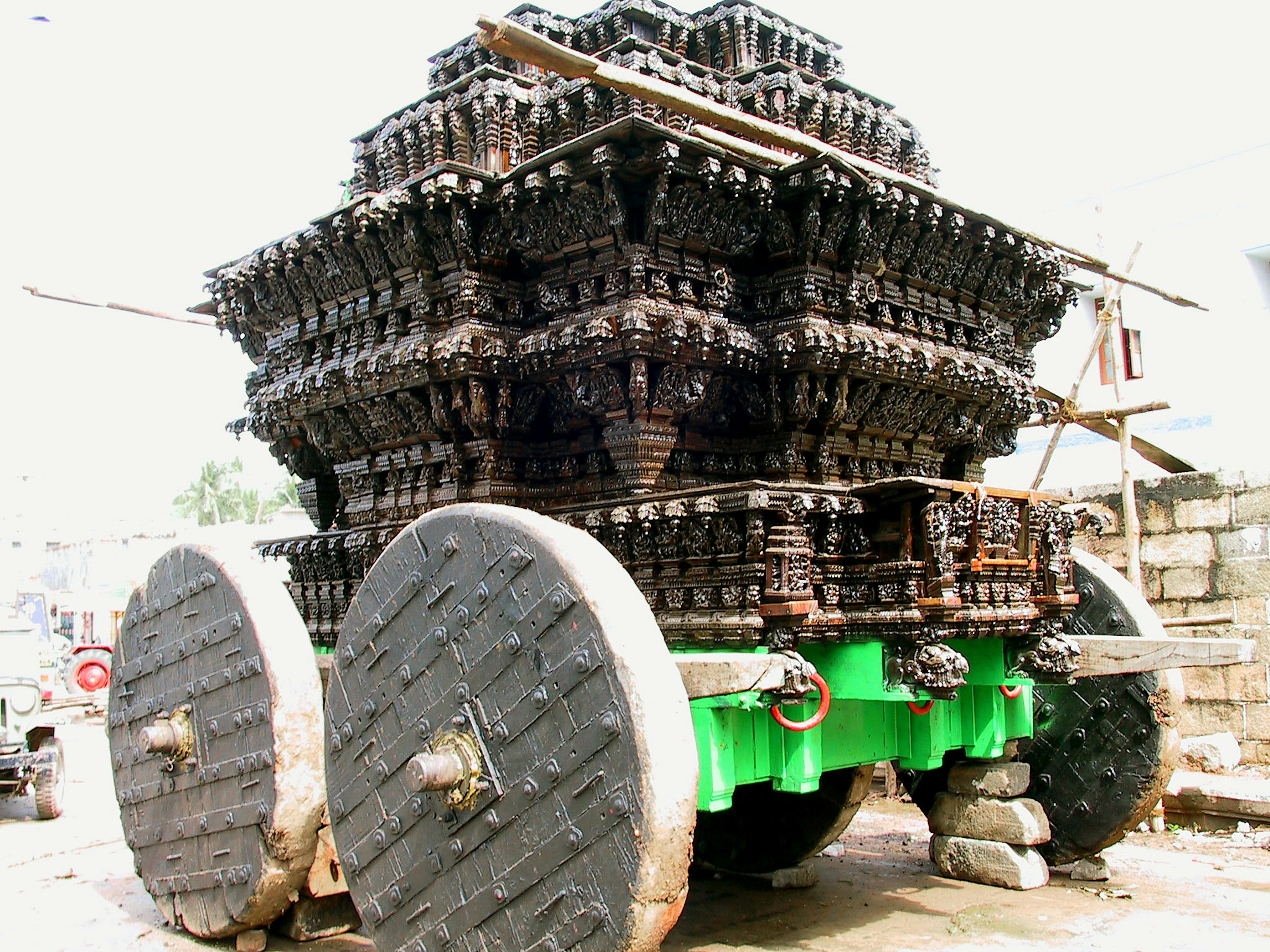 Grand véhicule avec des décorations noires complexes présentant des roues vertes et un cadre en bois