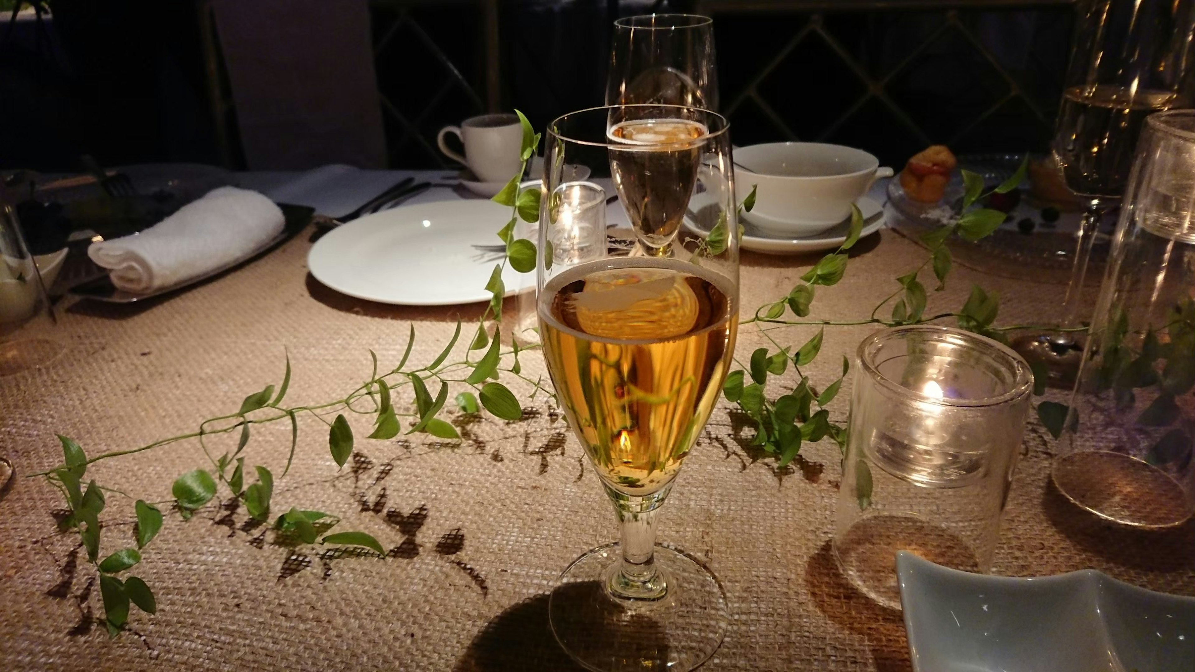 A scene featuring a glass of champagne on a table with decorative greenery