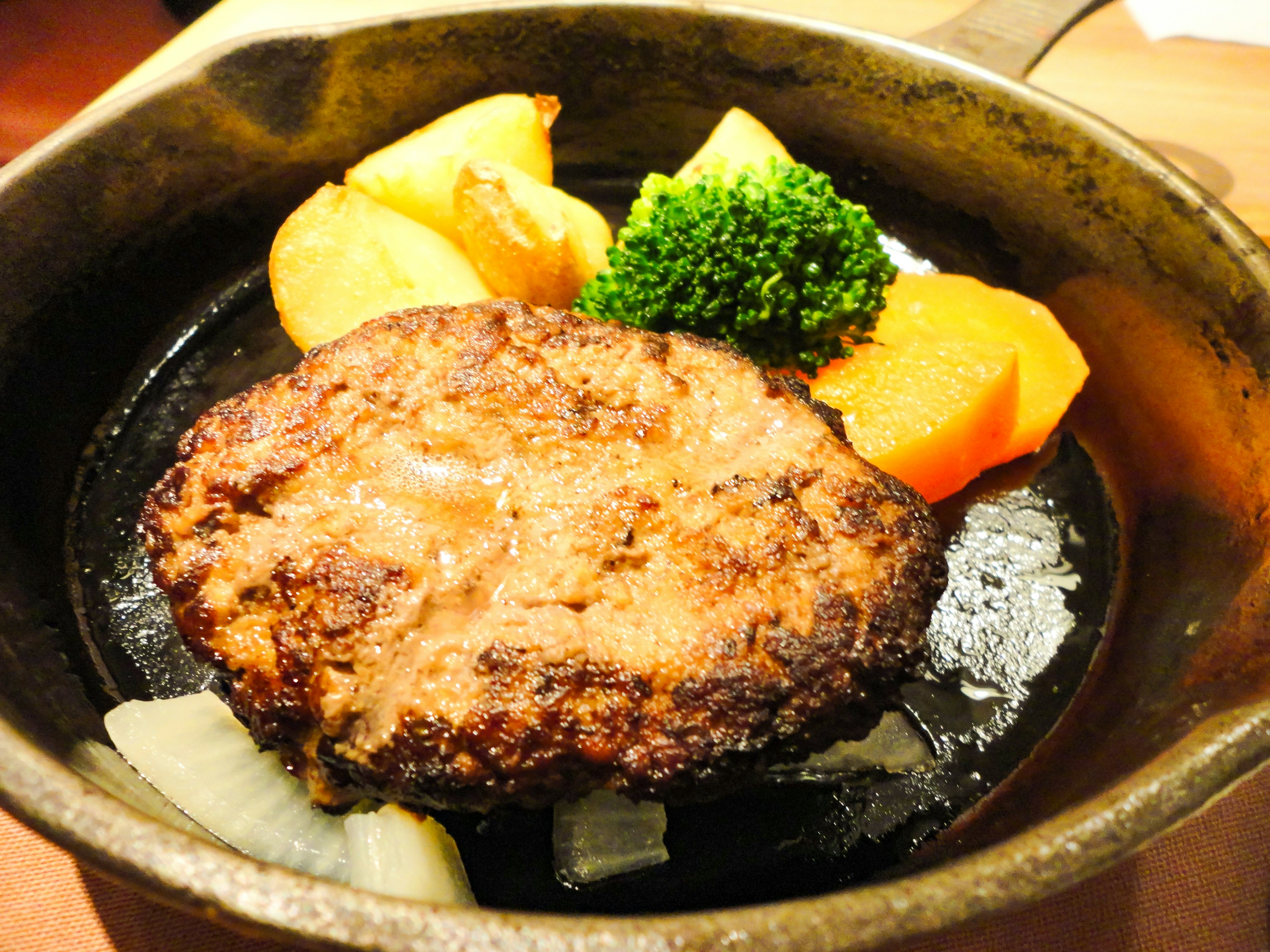 Sizzling hamburger steak served on a hot plate with vegetables