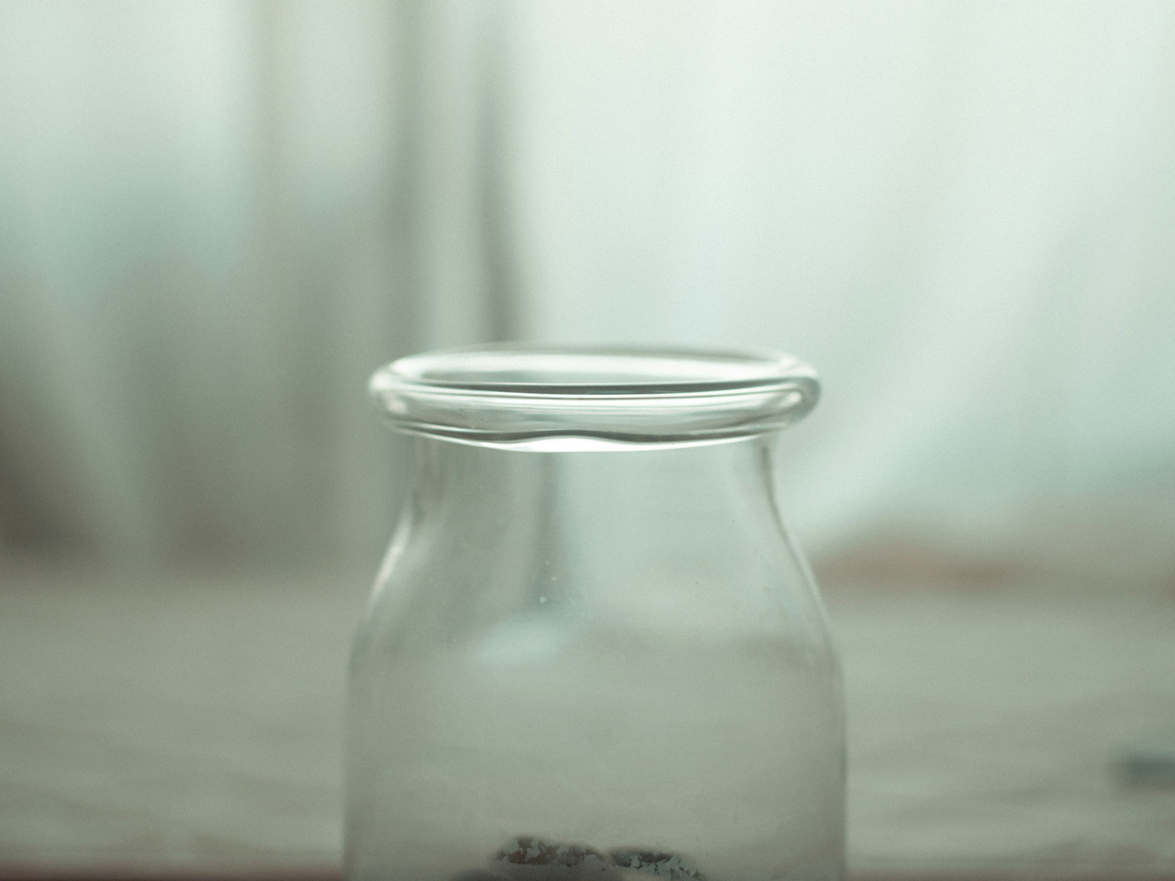 A transparent glass jar with a focus on the upper rim containing an unclear object inside