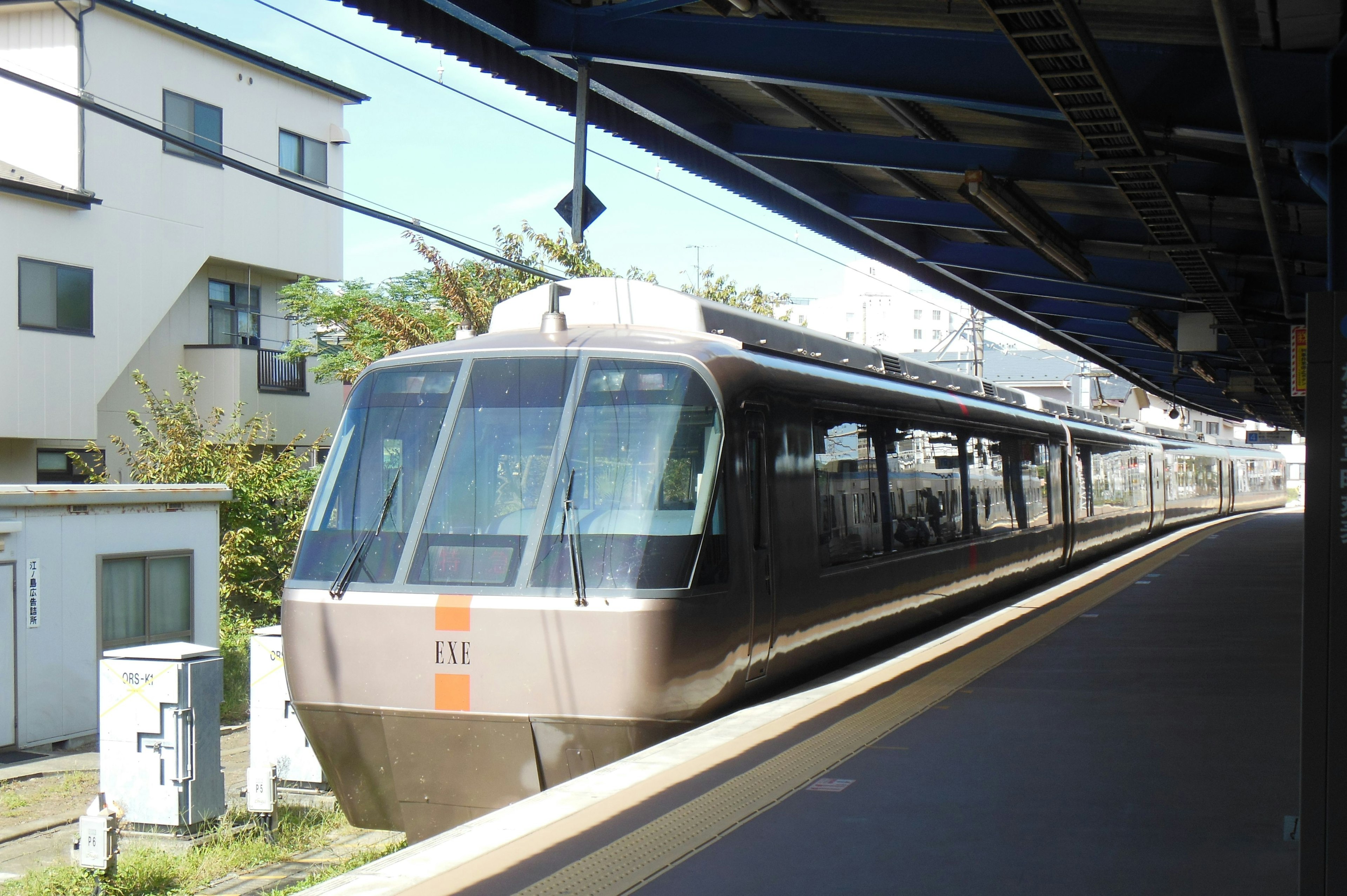 Treno moderno fermo in stazione con edifici circostanti