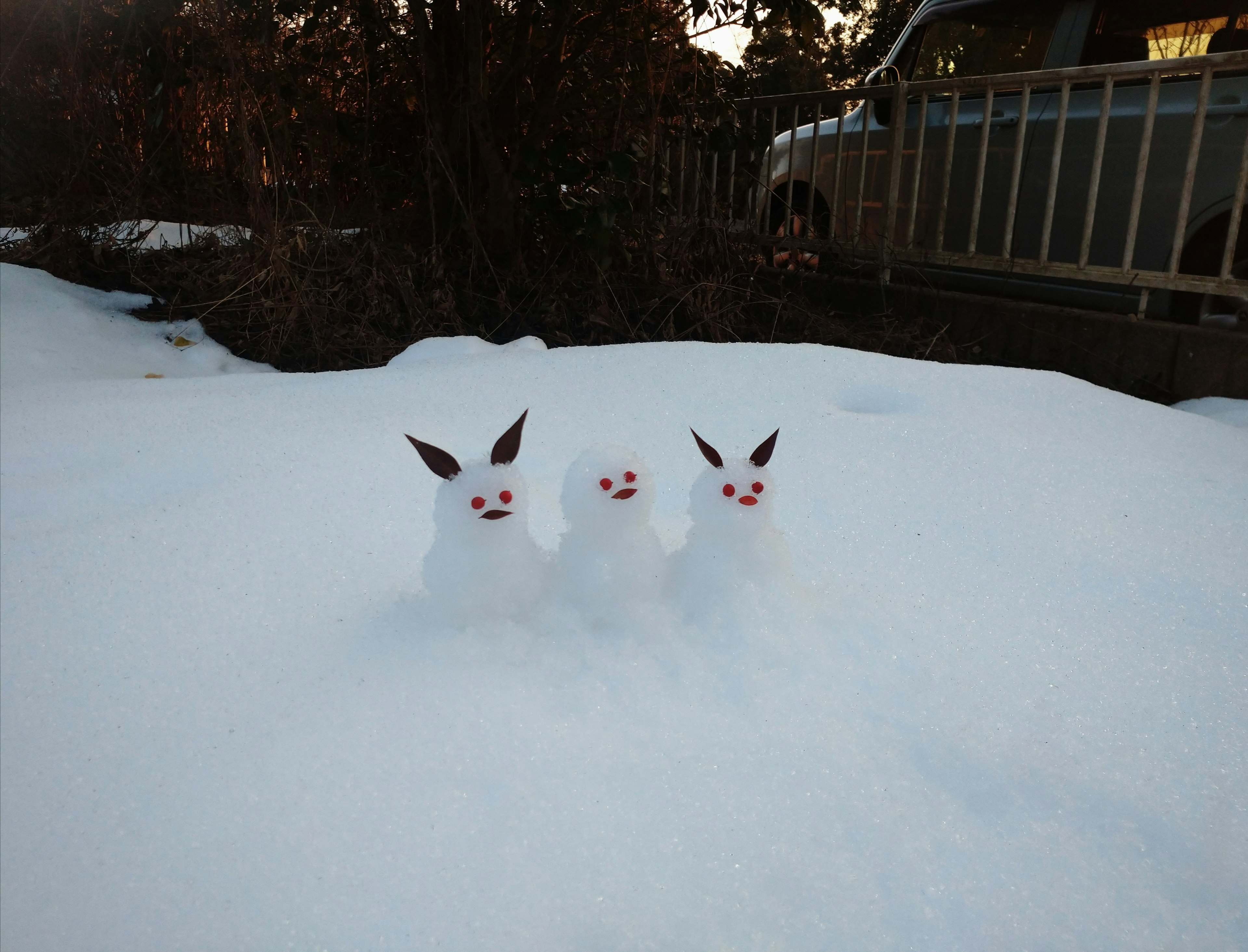 雪の中にいる三匹の白いウサギの置物