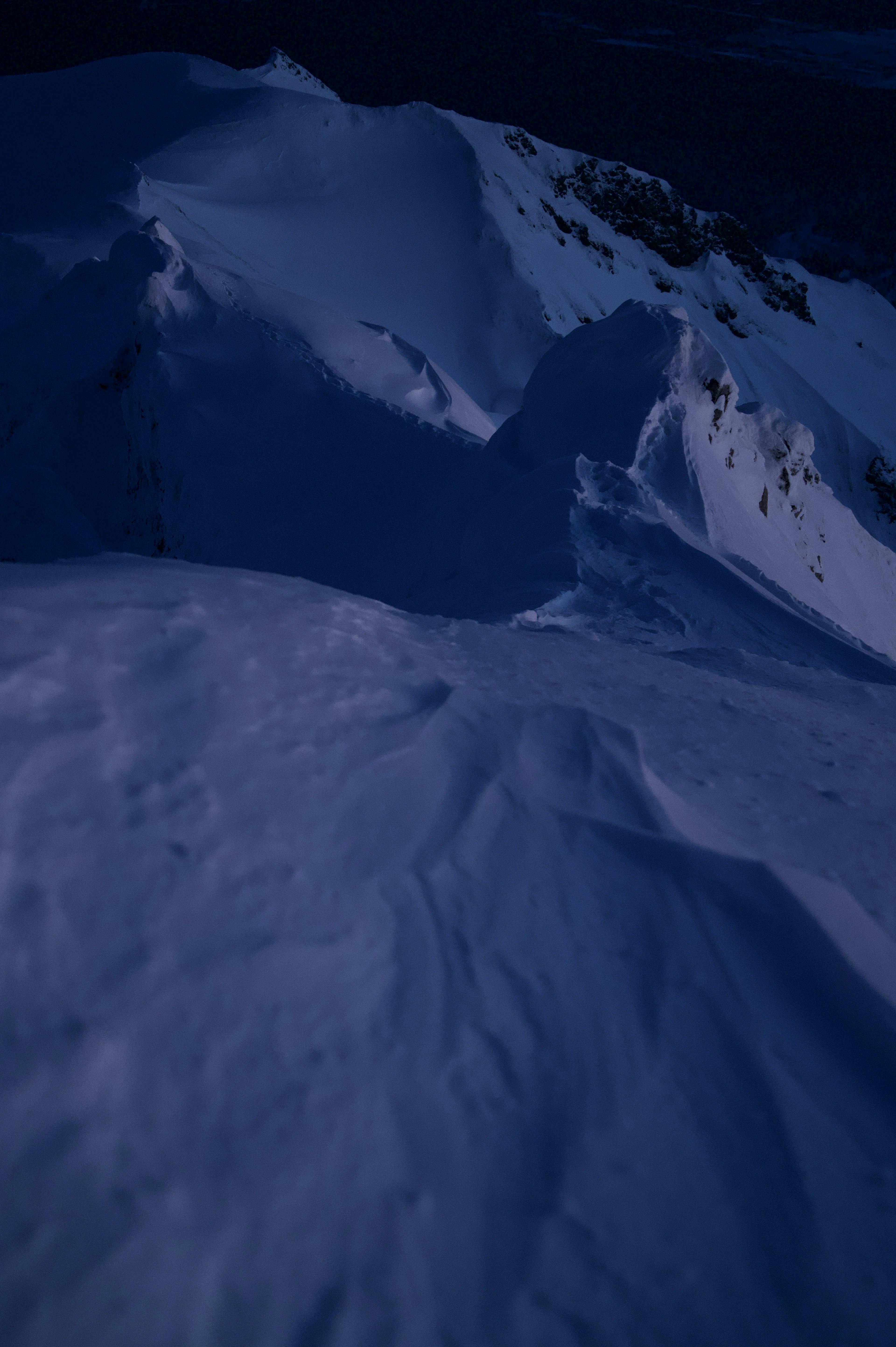 Photographie sombre d'une pente montagneuse recouverte de neige