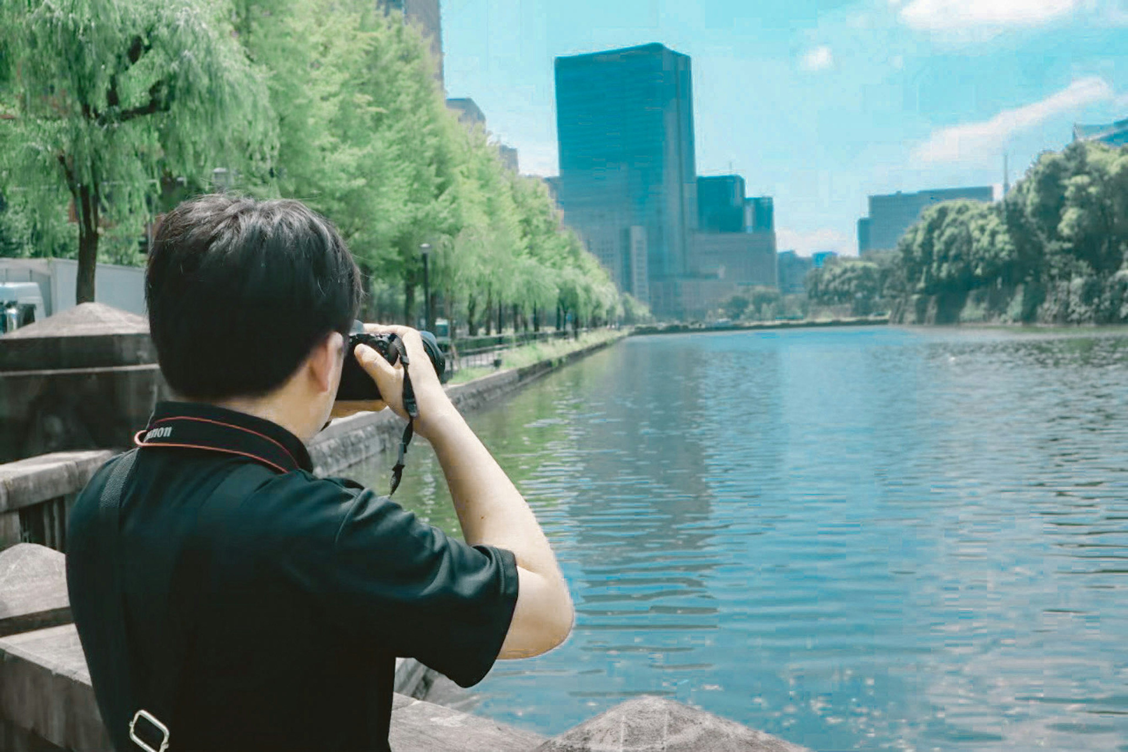 Hombre con cámara cerca del río capturando el paisaje urbano