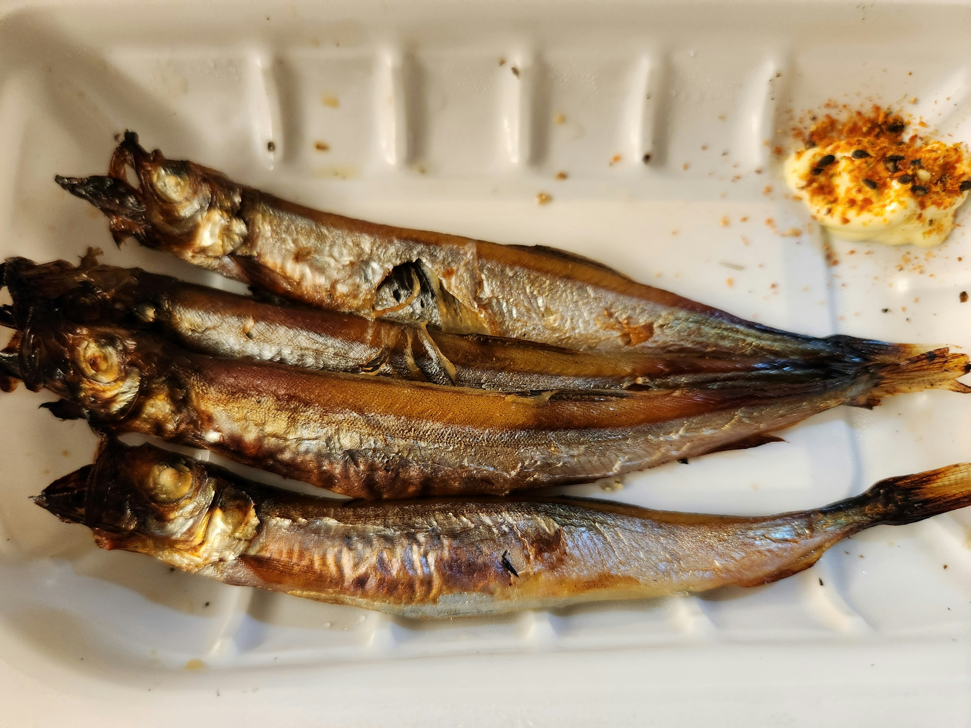 焼き魚の皿に盛られた四匹の小魚と焼きたての香ばしい料理