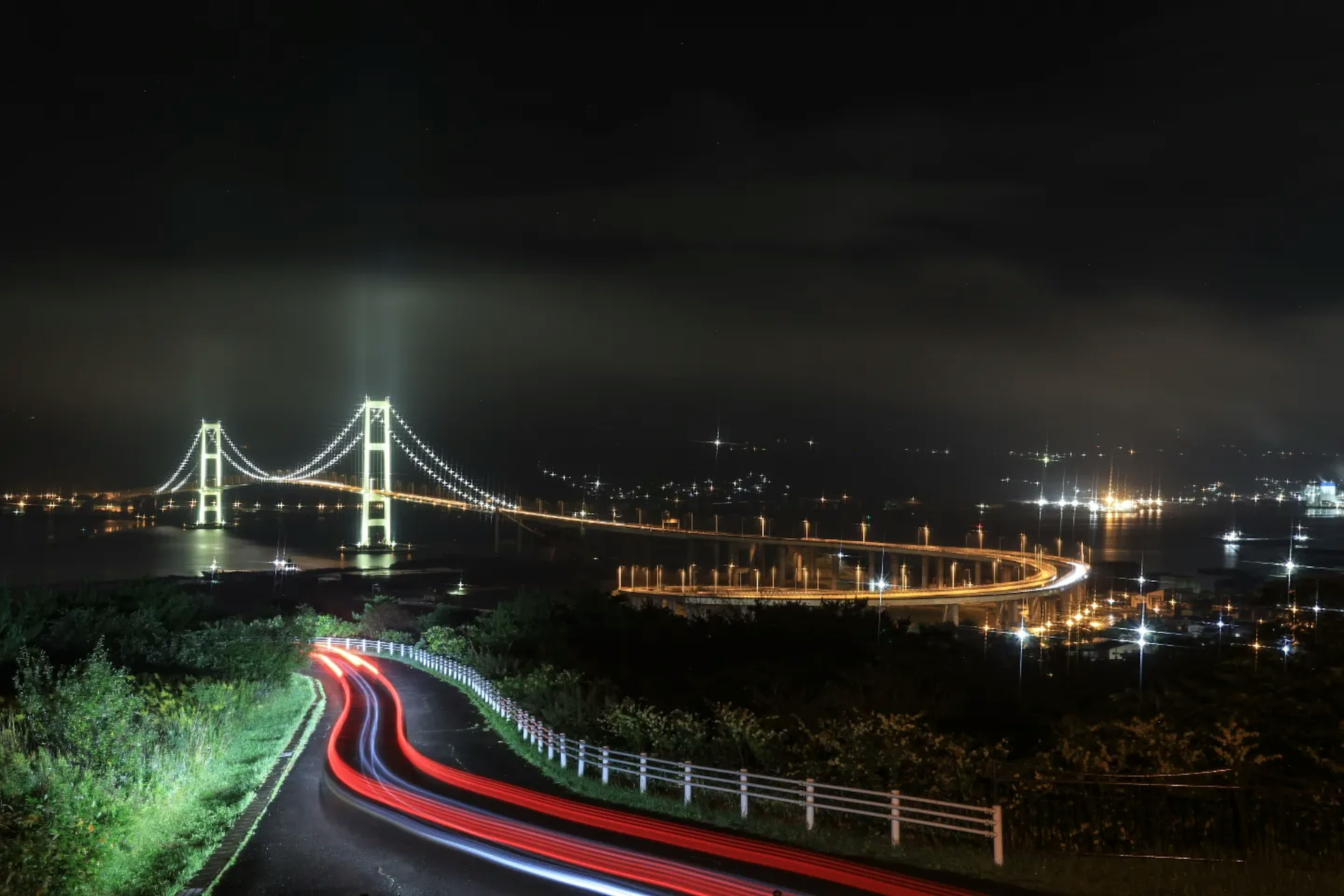 Puente Akashi Kaikyō iluminado de noche con estelas de luz de vehículos