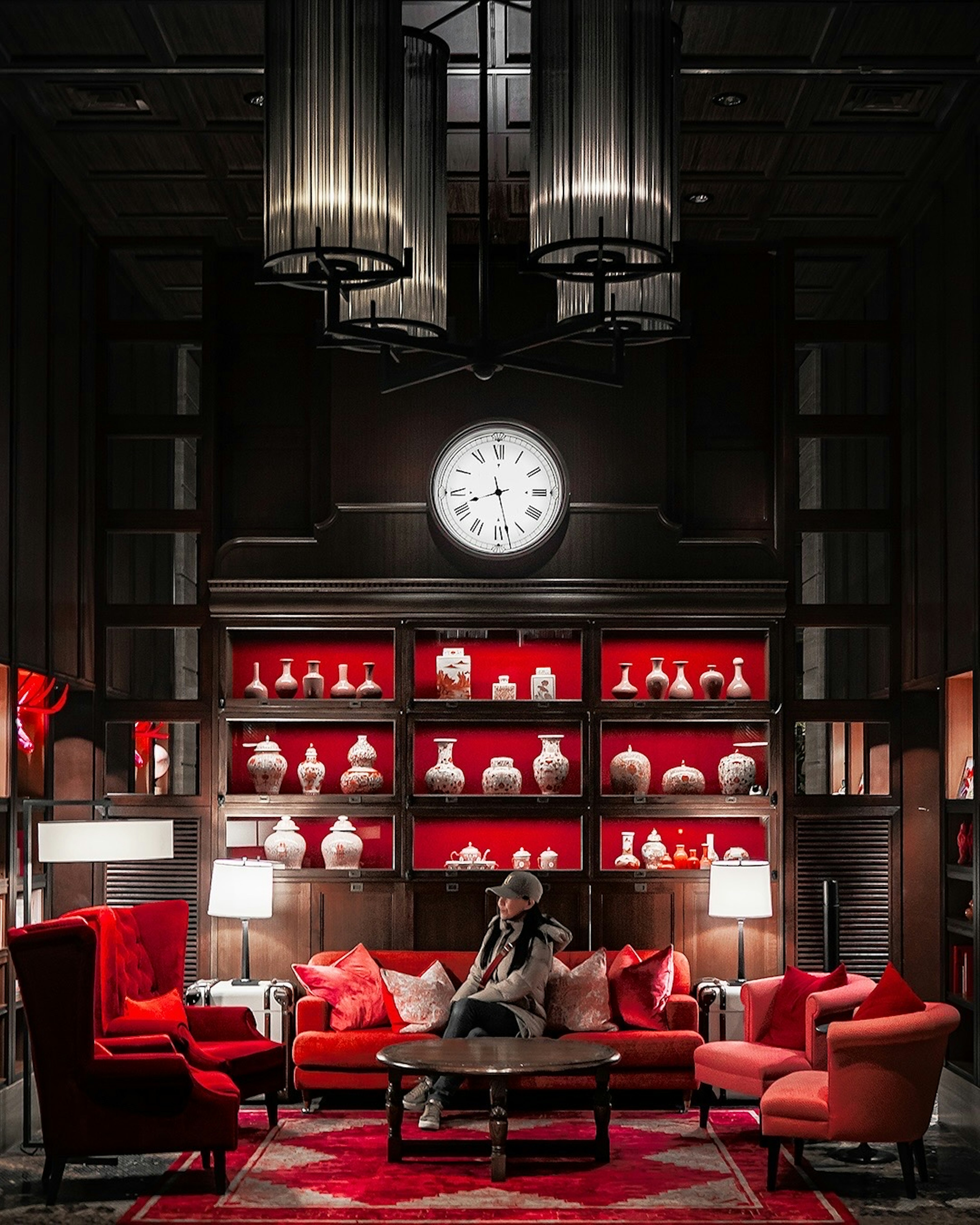 Luxurious lounge area with red and black tones featuring a person seated and decorative lighting