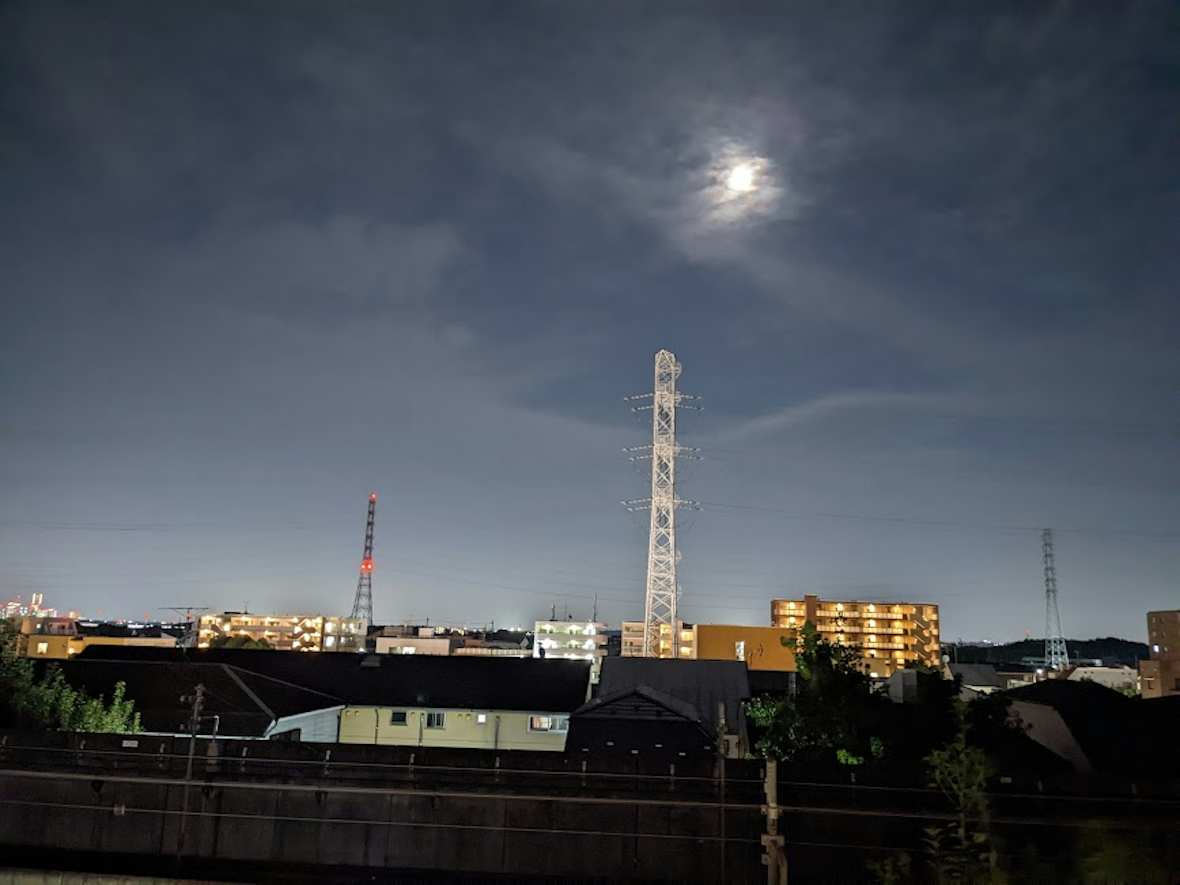 夜间城市风景，明亮的月亮和高通信塔