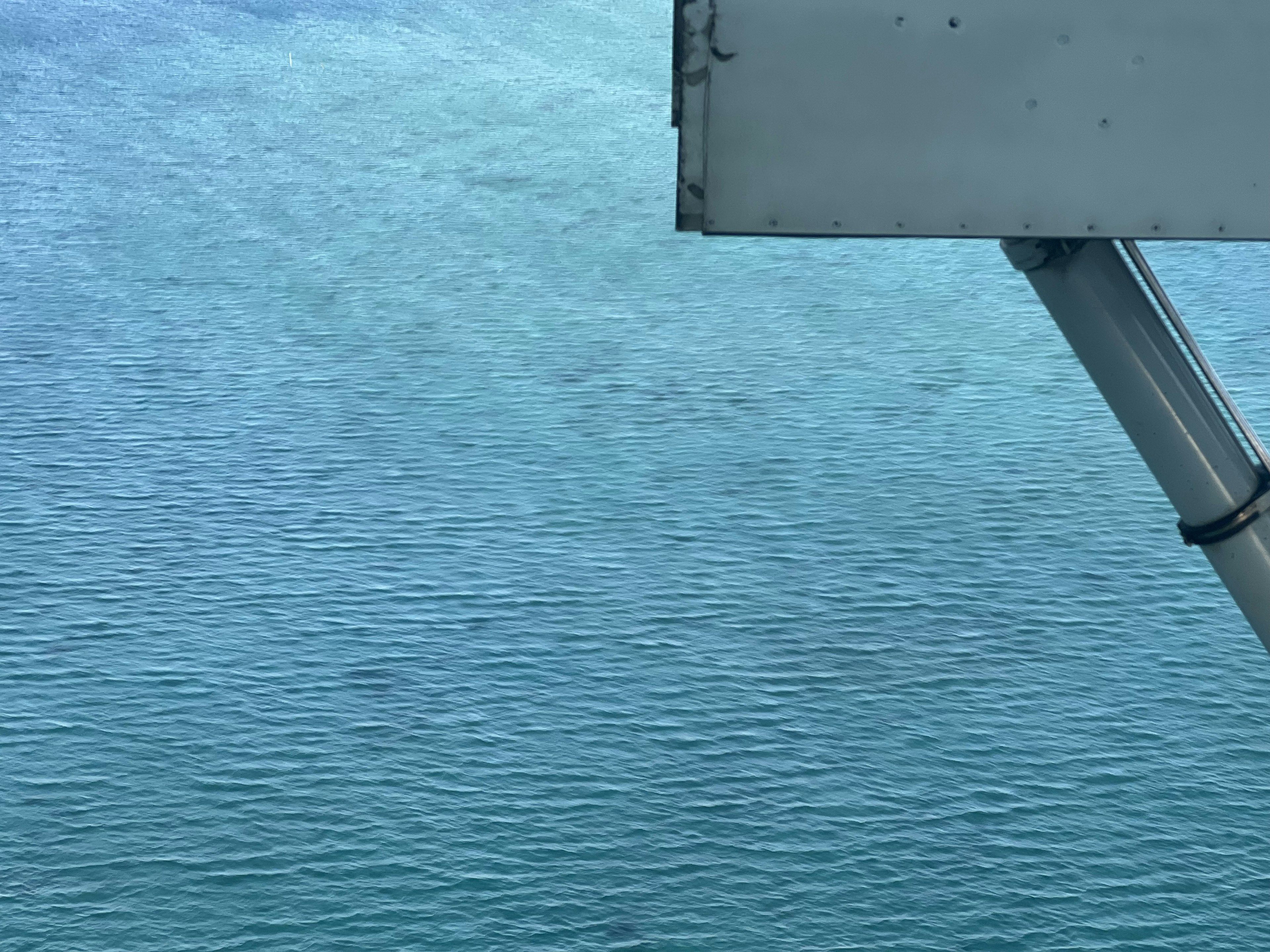 Vista de la superficie del agua azul del océano con parte de un barco