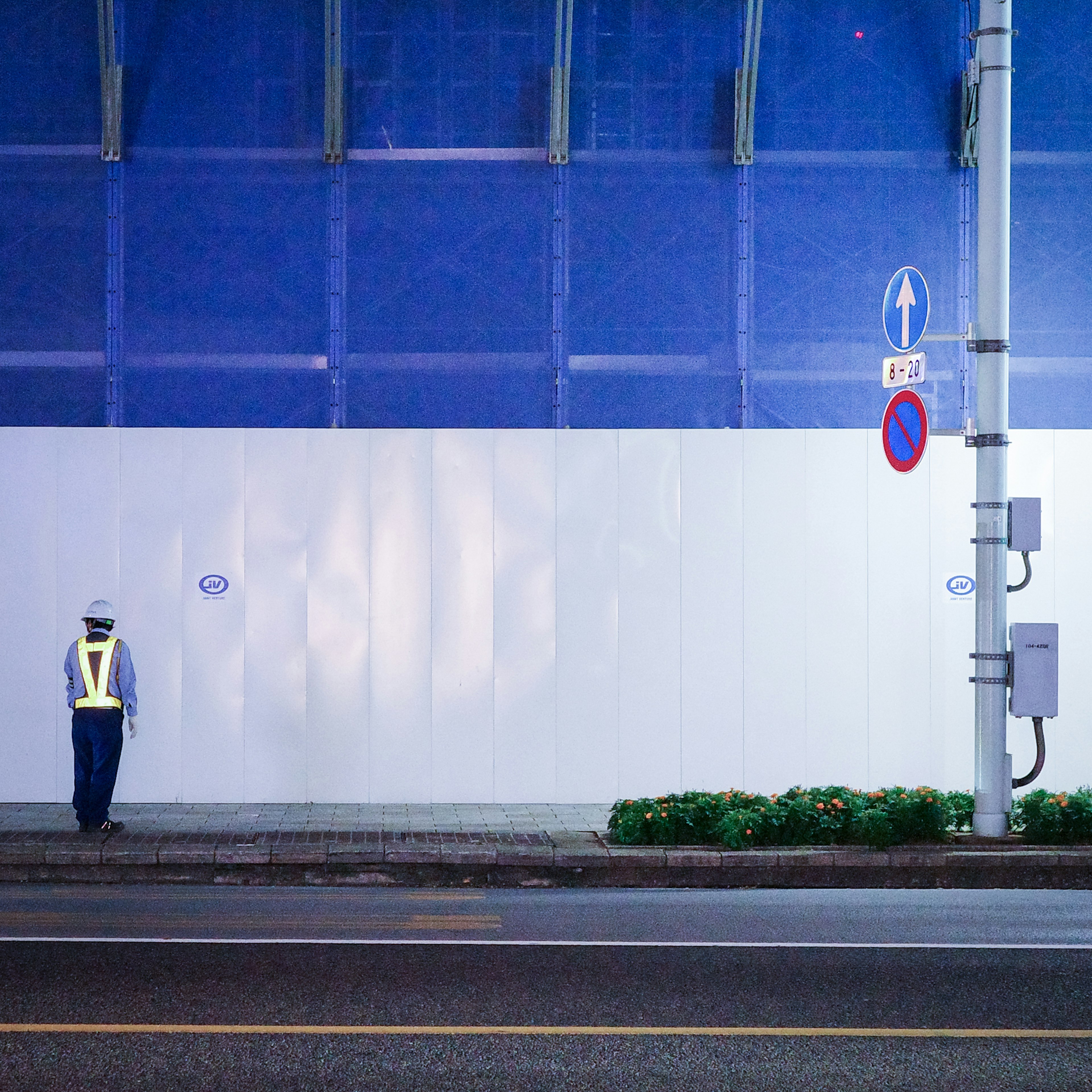 青い壁の前に立つ警備員の夜景