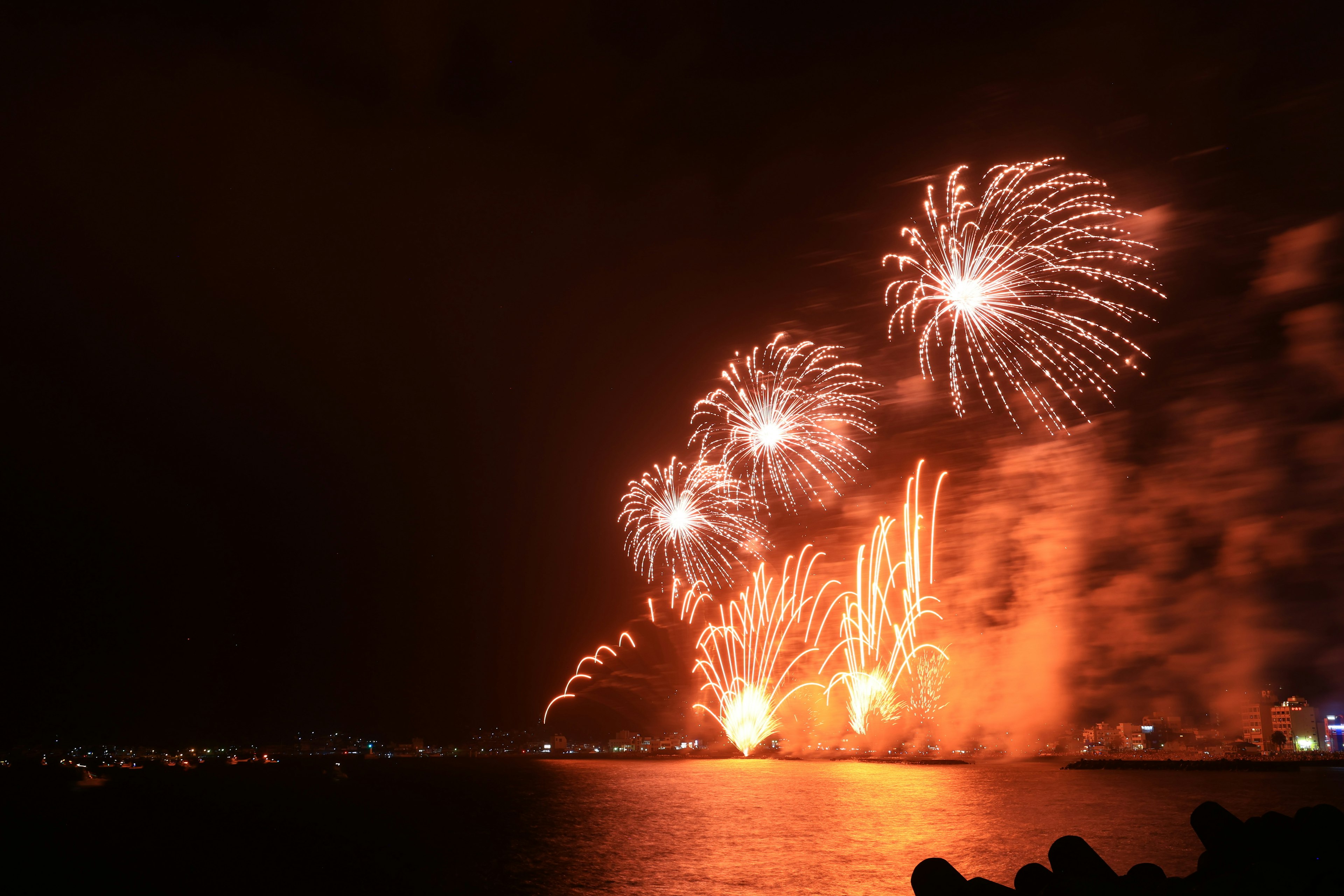 Lebhafte Feuerwerksvorführung über dem Wasser bei Nacht