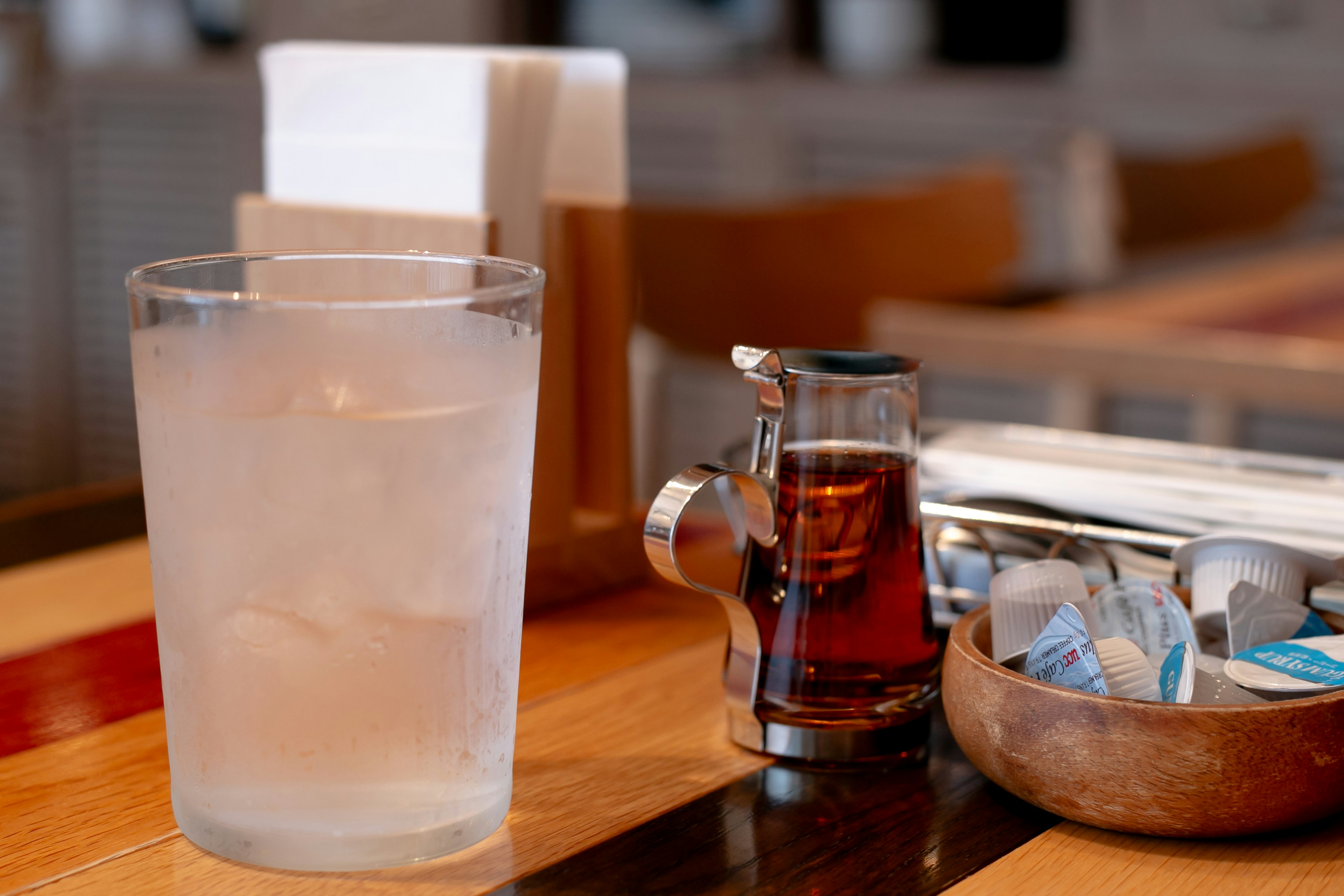 Ein Foto von einem Glas mit Eiswasser und einer kleinen Sirupflasche auf einem Tisch