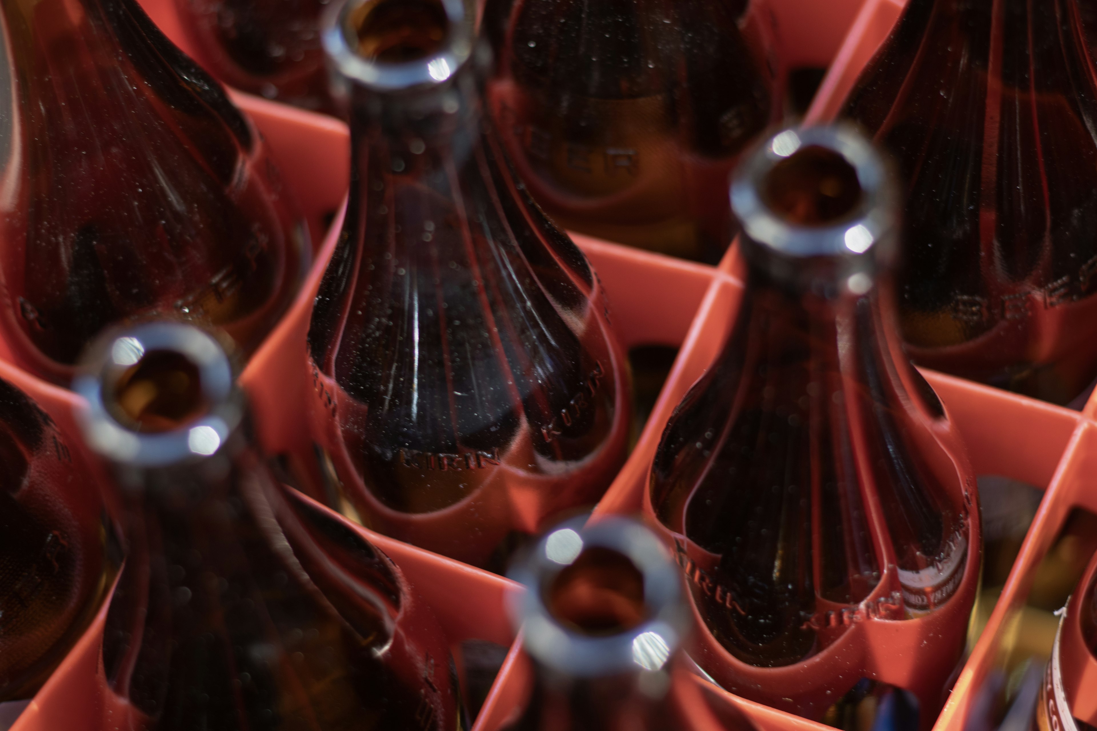 Brown bottles arranged in a pink carton