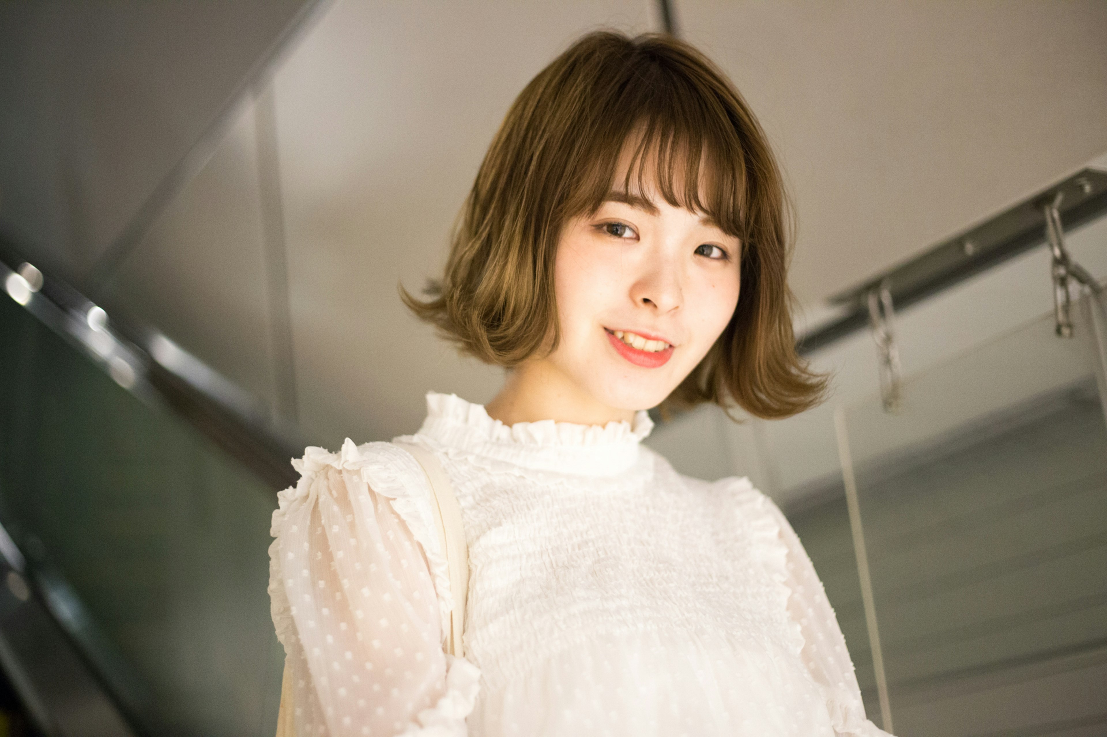 Portrait of a woman wearing a white blouse smiling with soft hairstyle blurred urban background