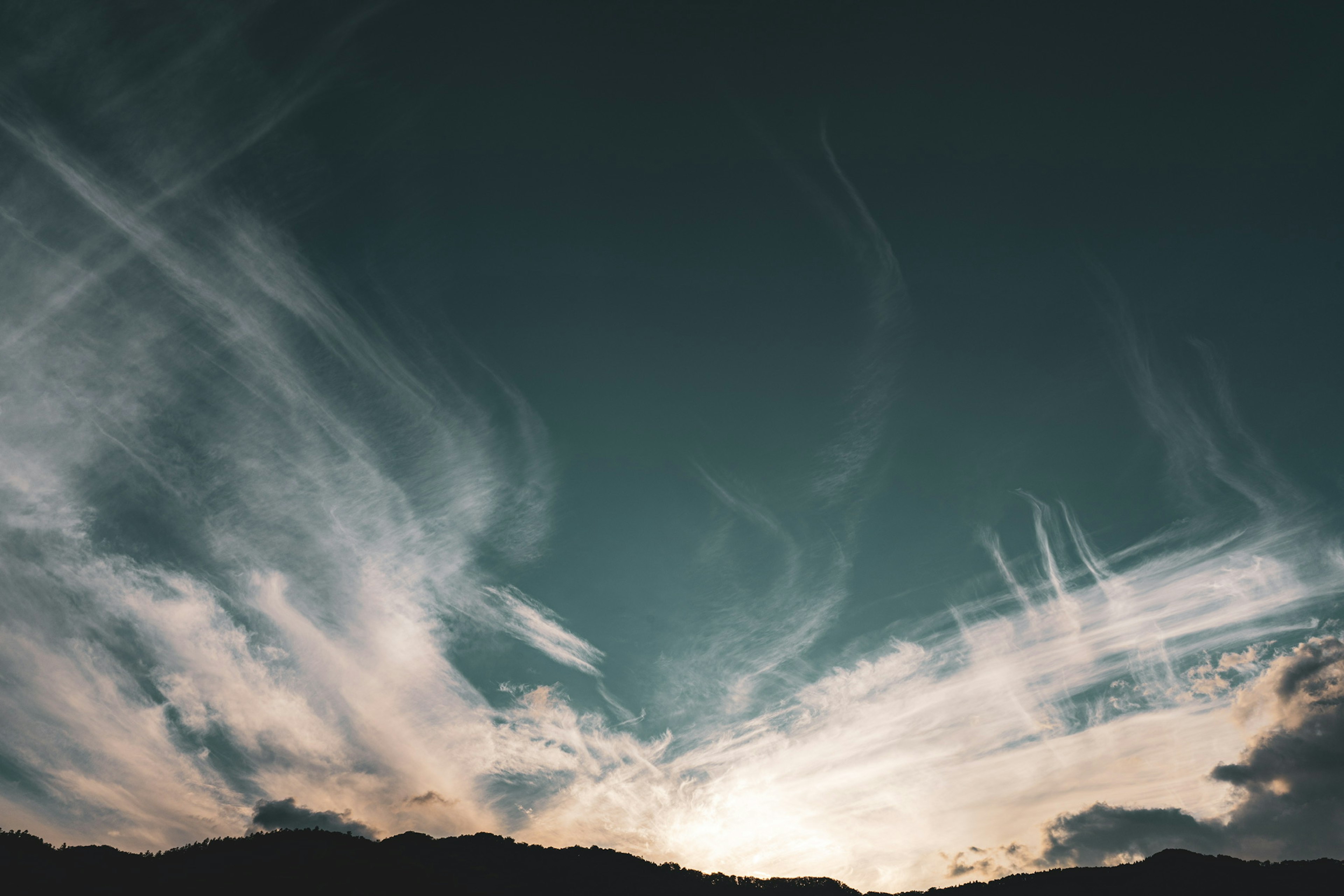 Nuages tourbillonnants dans un ciel bleu avec silhouette de montagne