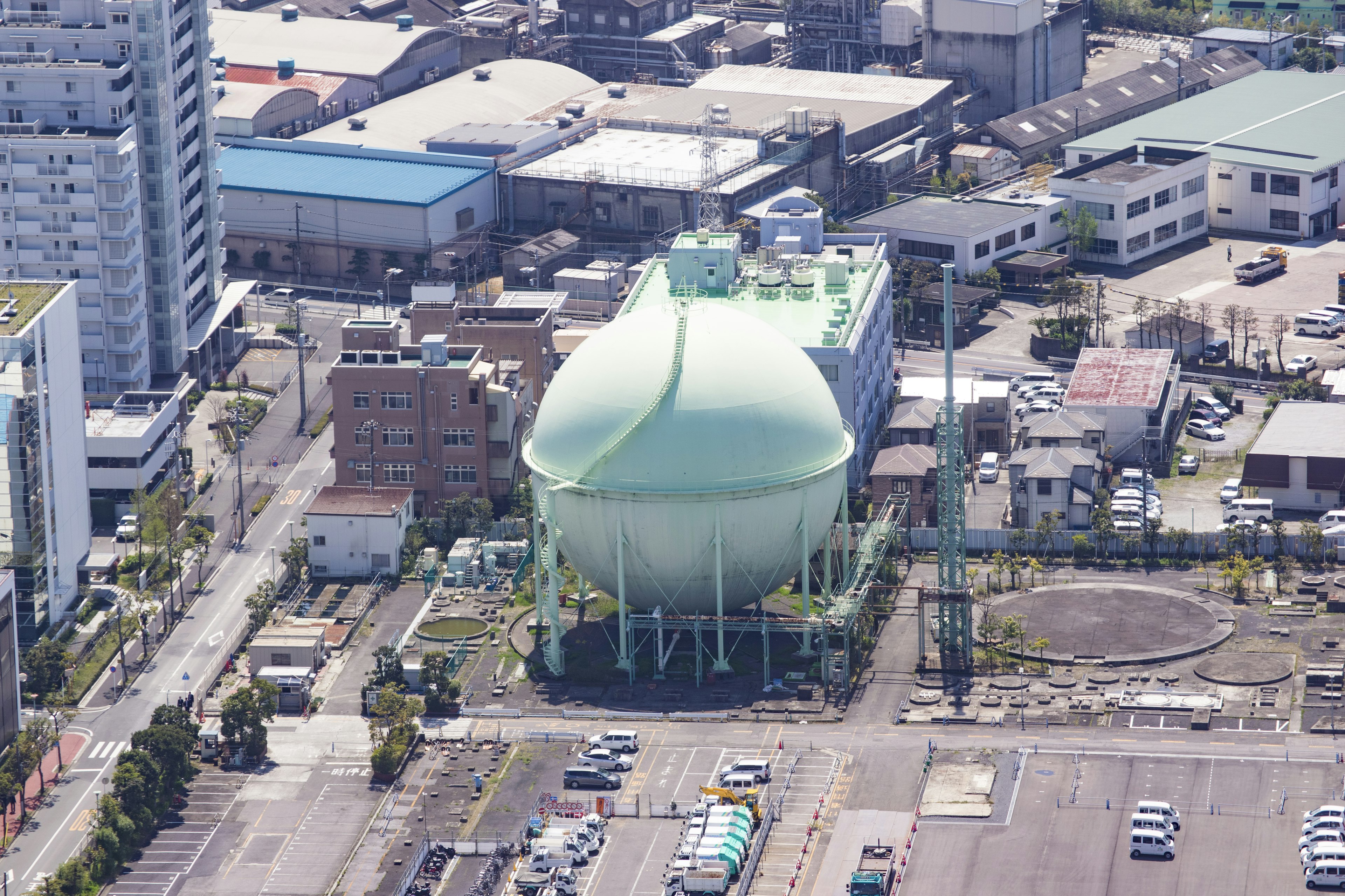 Grande cisterna verde circondata da un paesaggio urbano