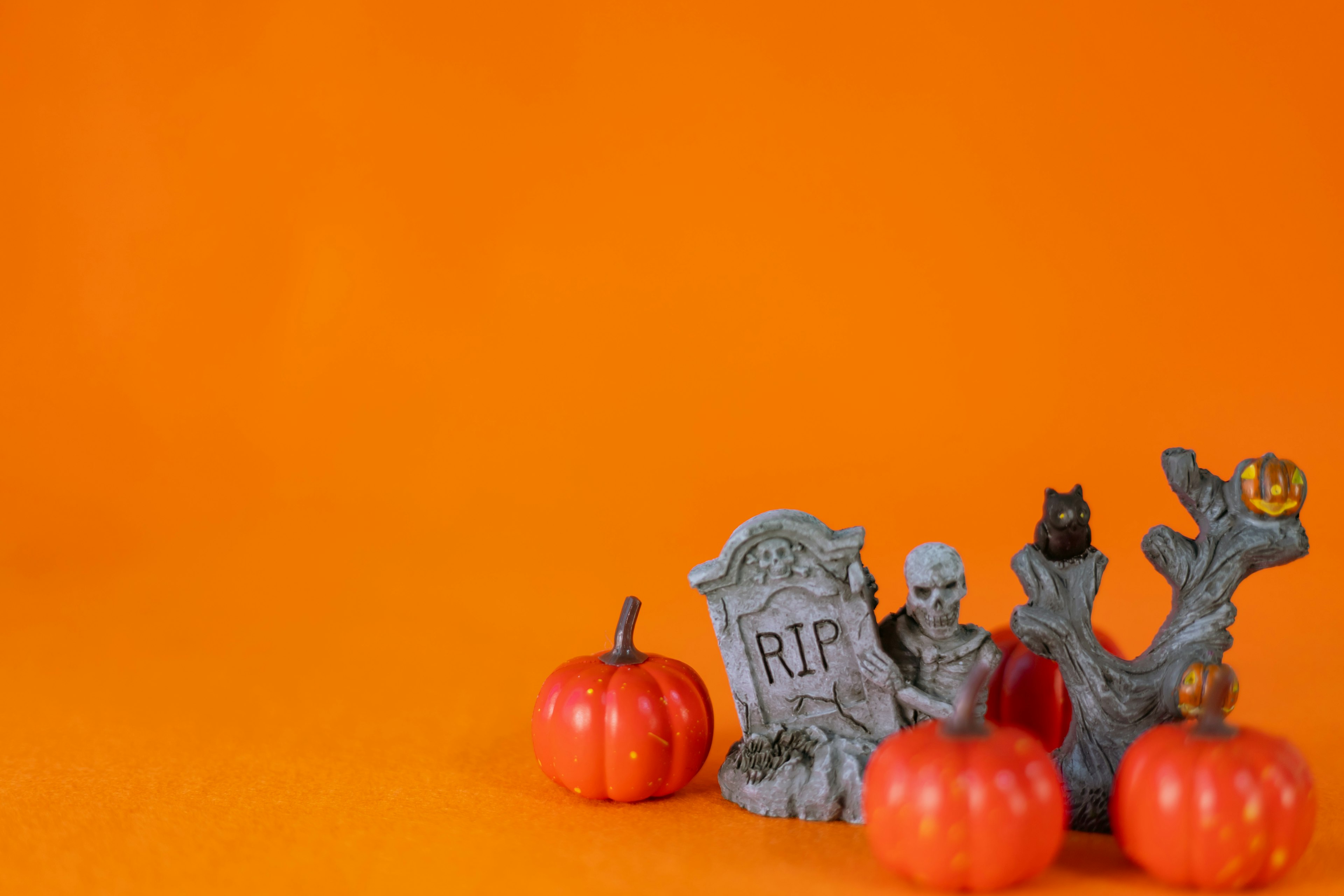 Un conjunto de decoraciones de Halloween y calabazas dispuestas sobre un fondo naranja