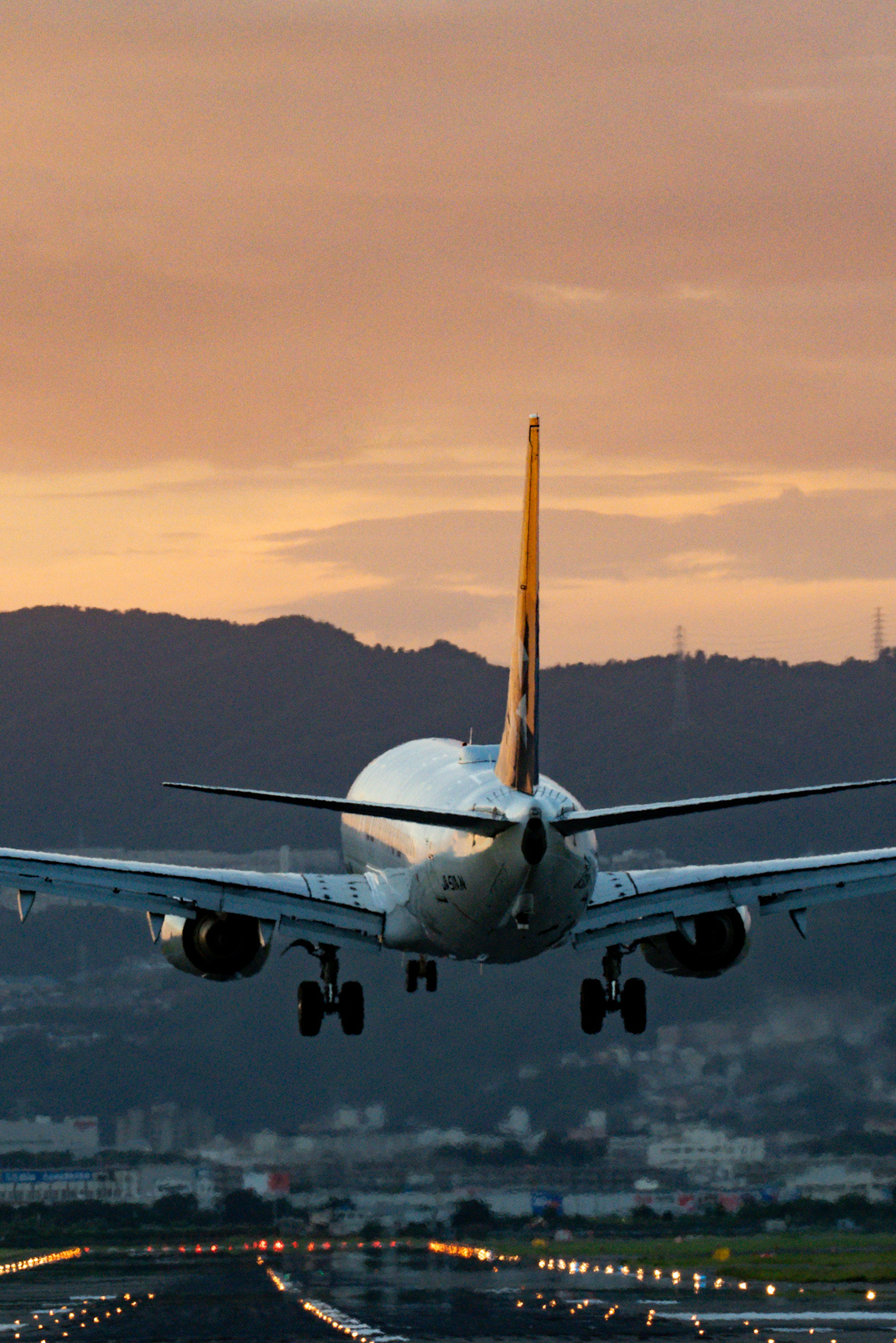 Avión aterrizando al atardecer con montañas de fondo