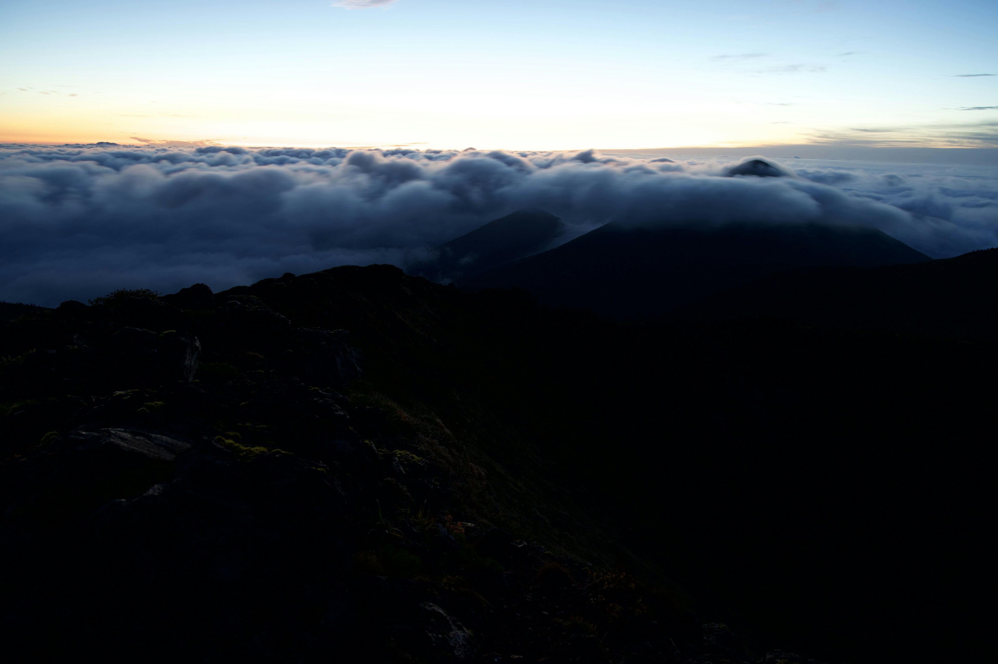 Vista di un mare di nuvole dalla cima di una montagna con cielo al tramonto