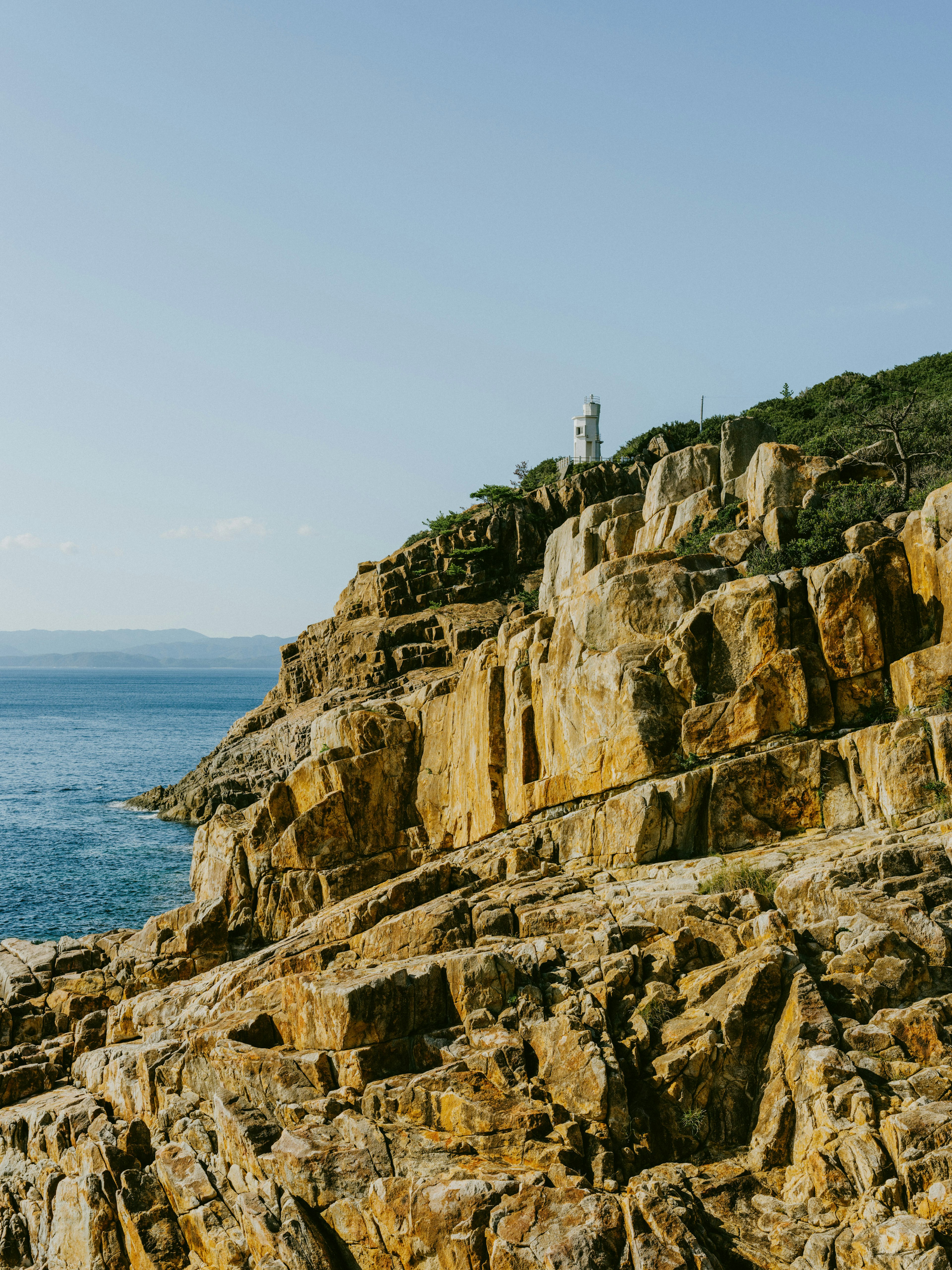 Scogliera rocciosa al mare con un faro sullo sfondo