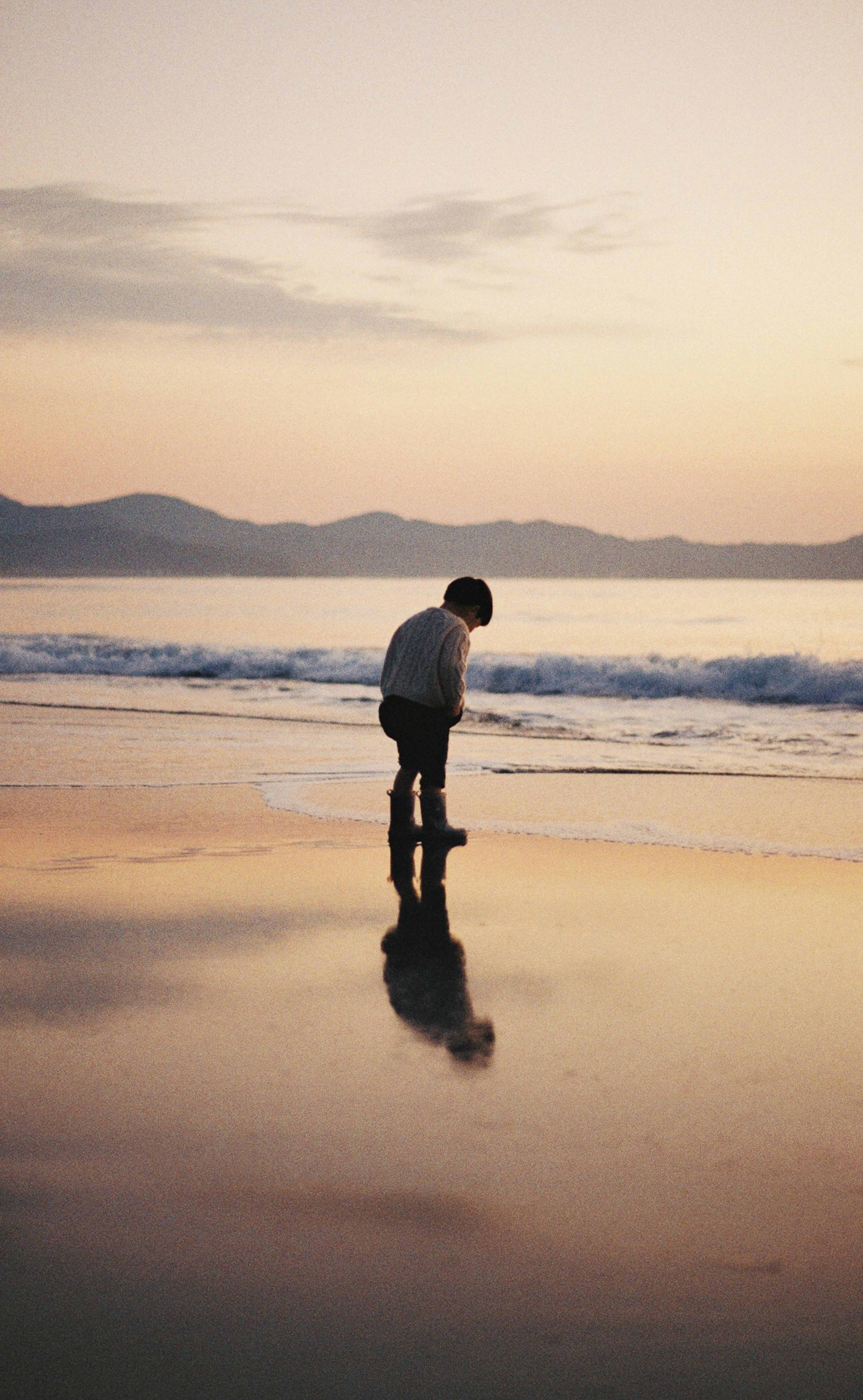 เงาของเด็กที่เล่นอยู่บนชายหาดในช่วงพระอาทิตย์ตก