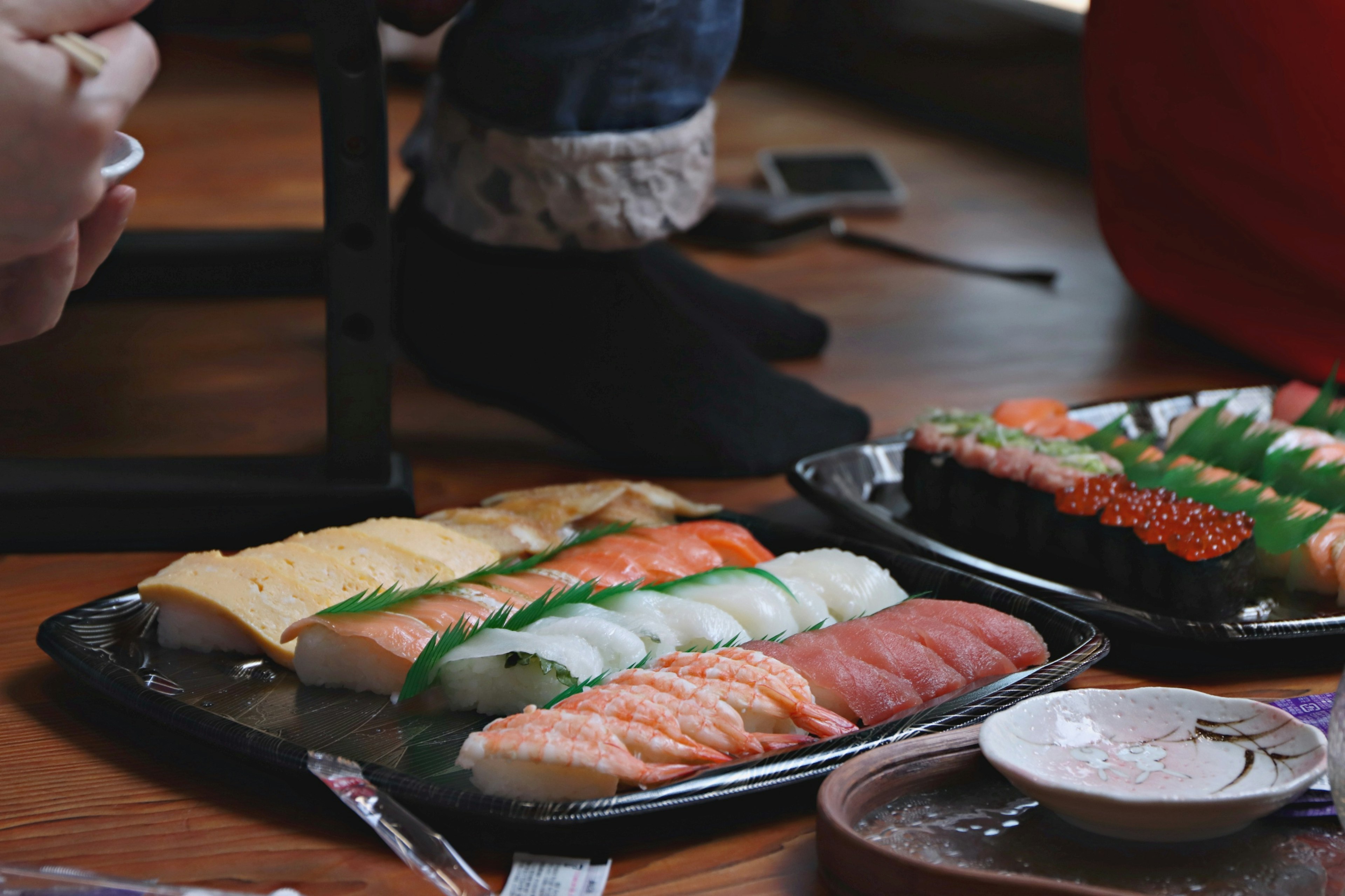 Piring sushi dengan berbagai jenis sushi dan kaki berkaos kaki