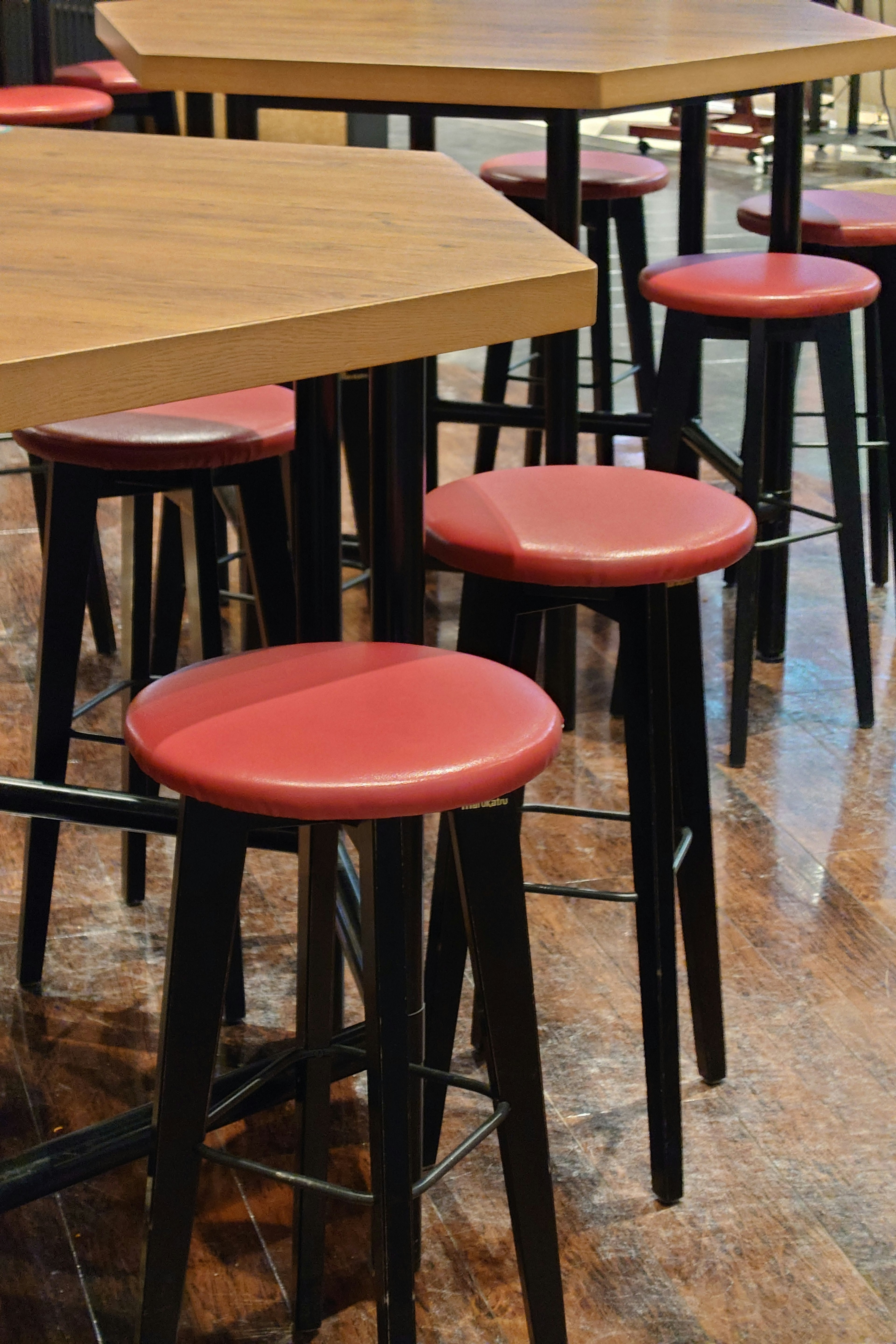 Counter stools with red seats and black legs alongside a wooden table