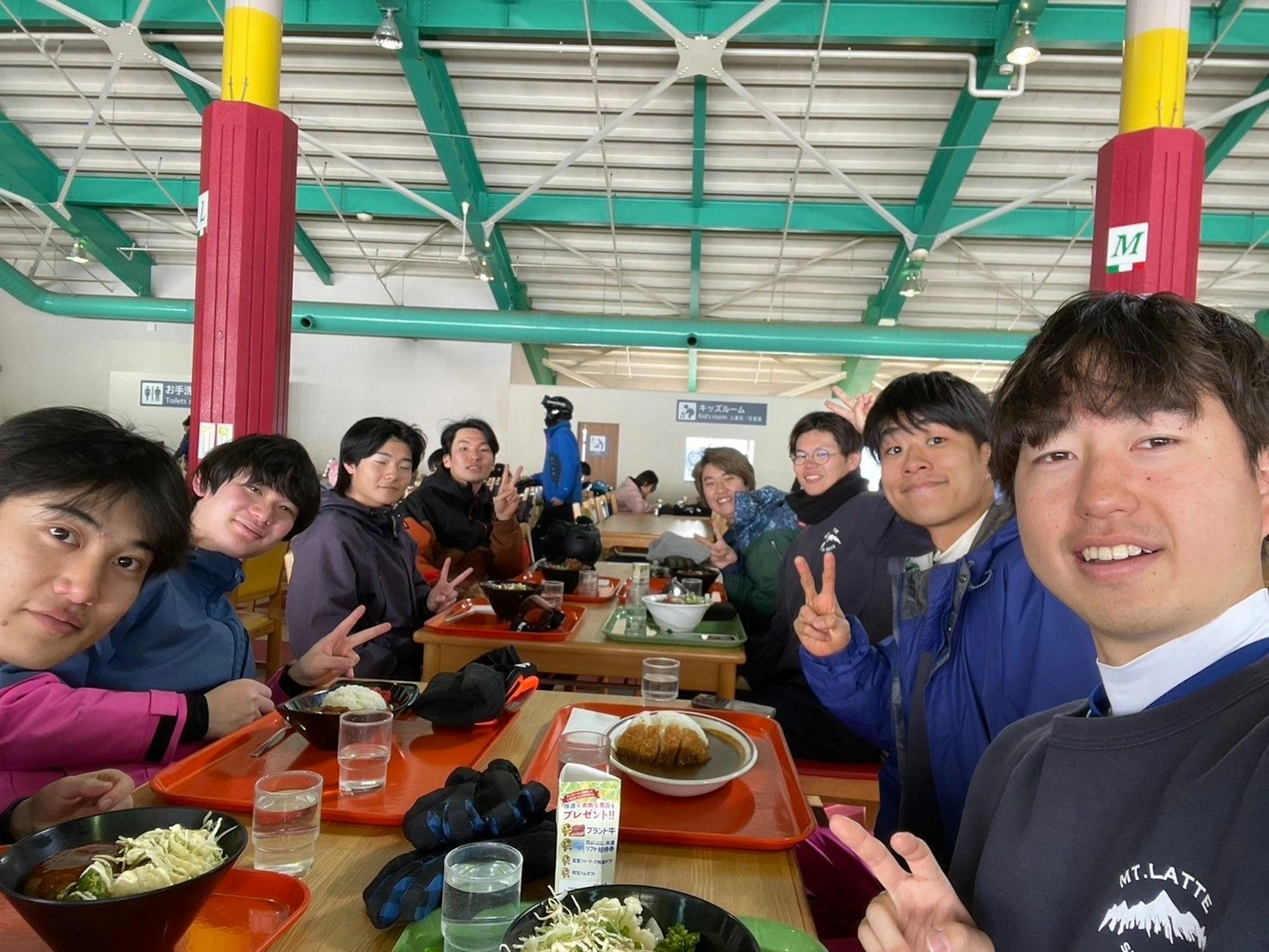 Un gruppo di giovani che si gode un pasto insieme facendo segni di pace verso la telecamera