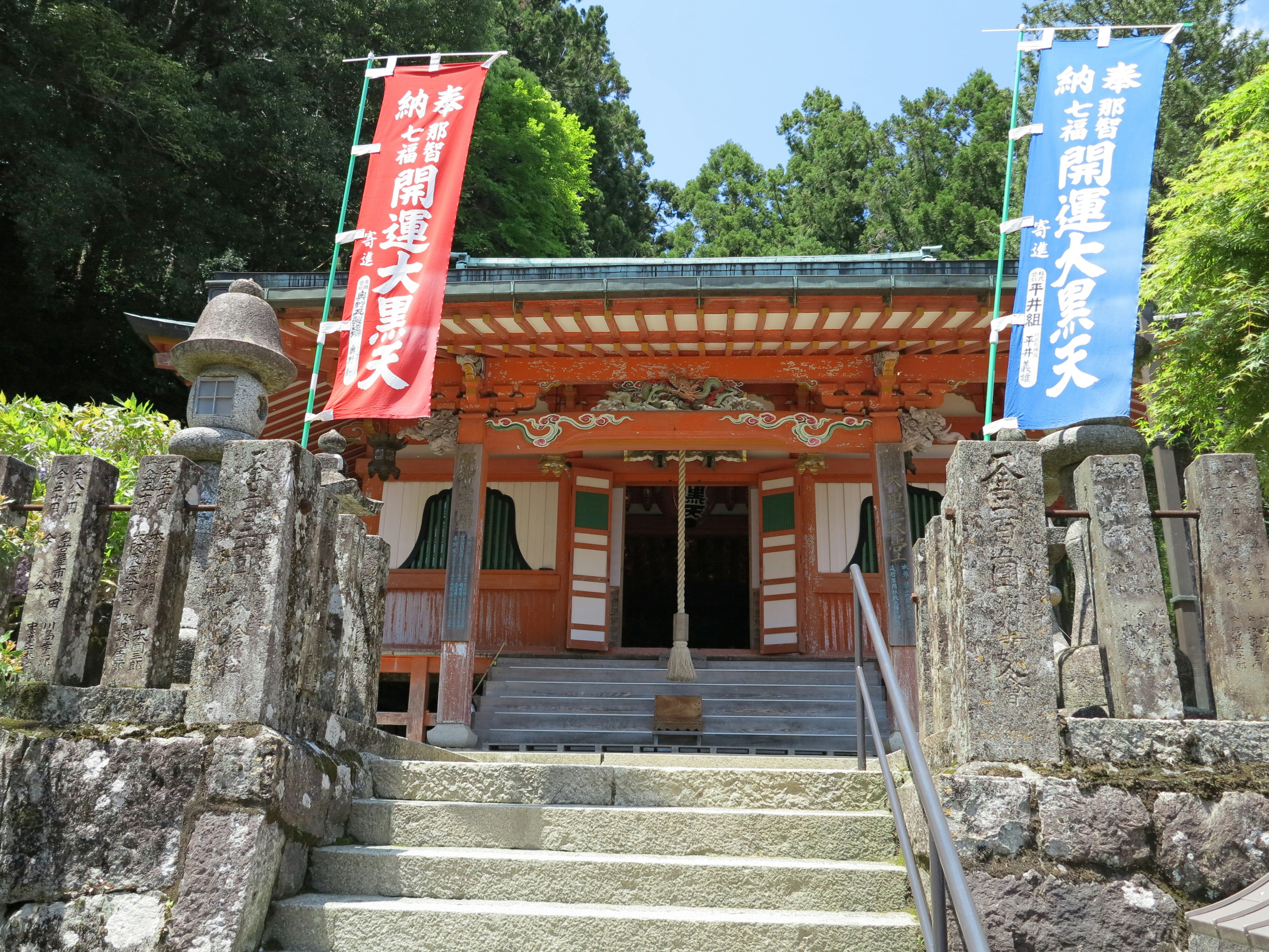 Entrance of a traditional shrine with stairs leading up Red and blue banners on either side