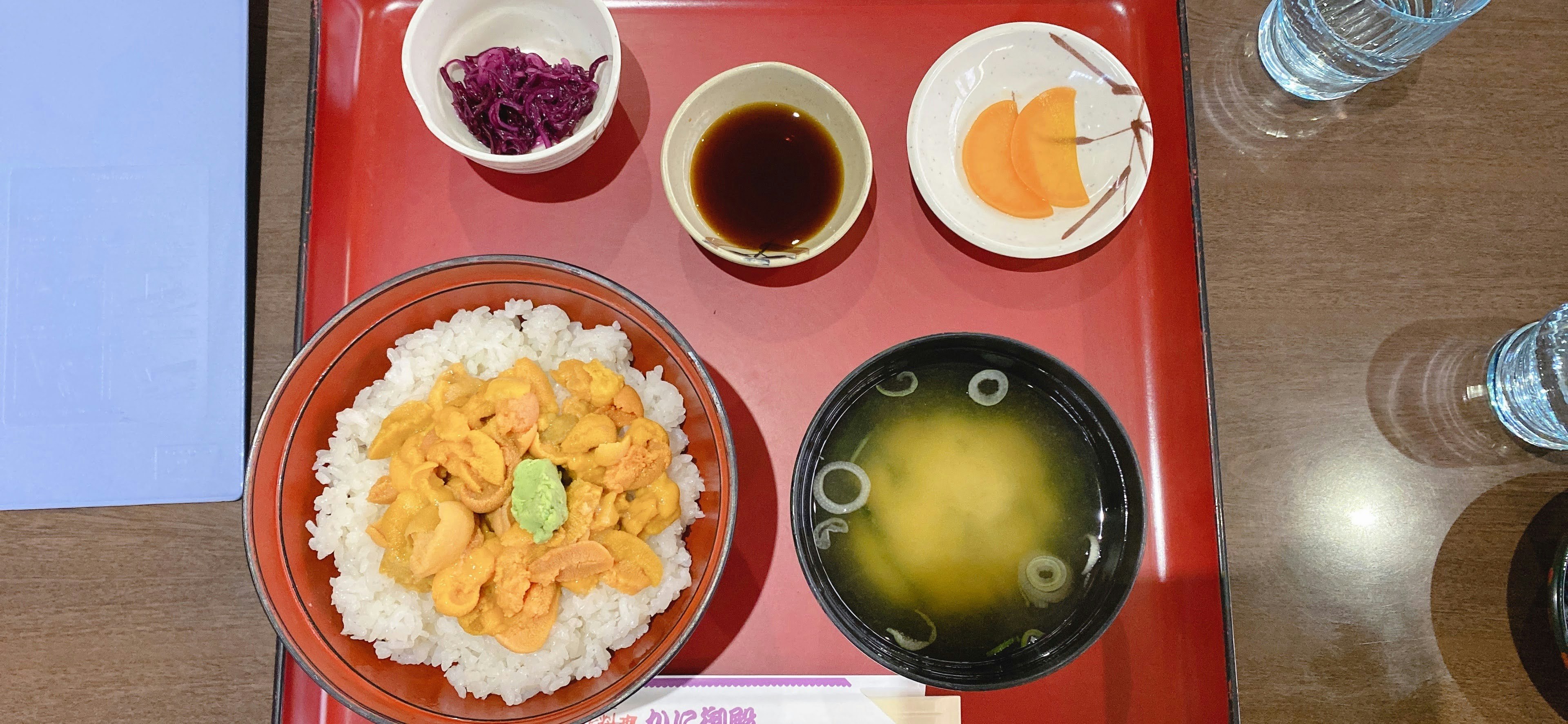 Tazón de arroz con mariscos servido en una bandeja roja con sopa de miso y condimentos