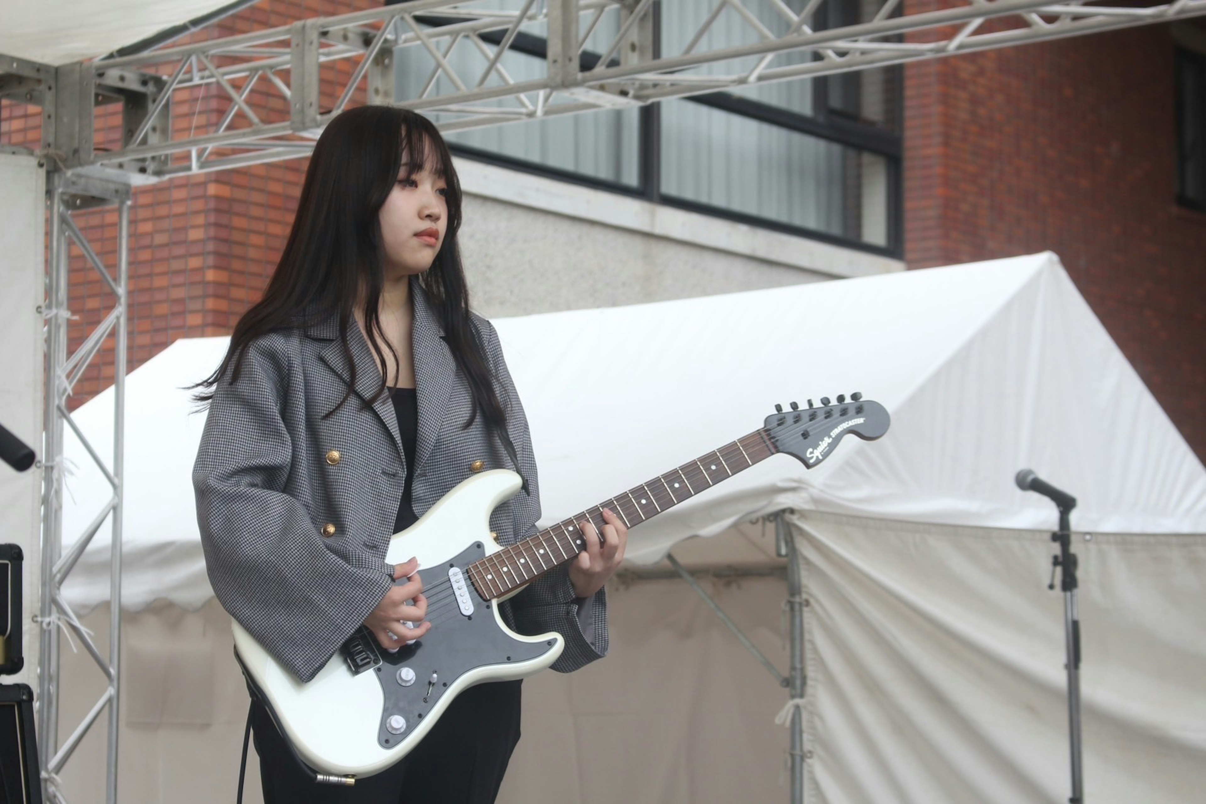 Female musician on stage holding a white guitar