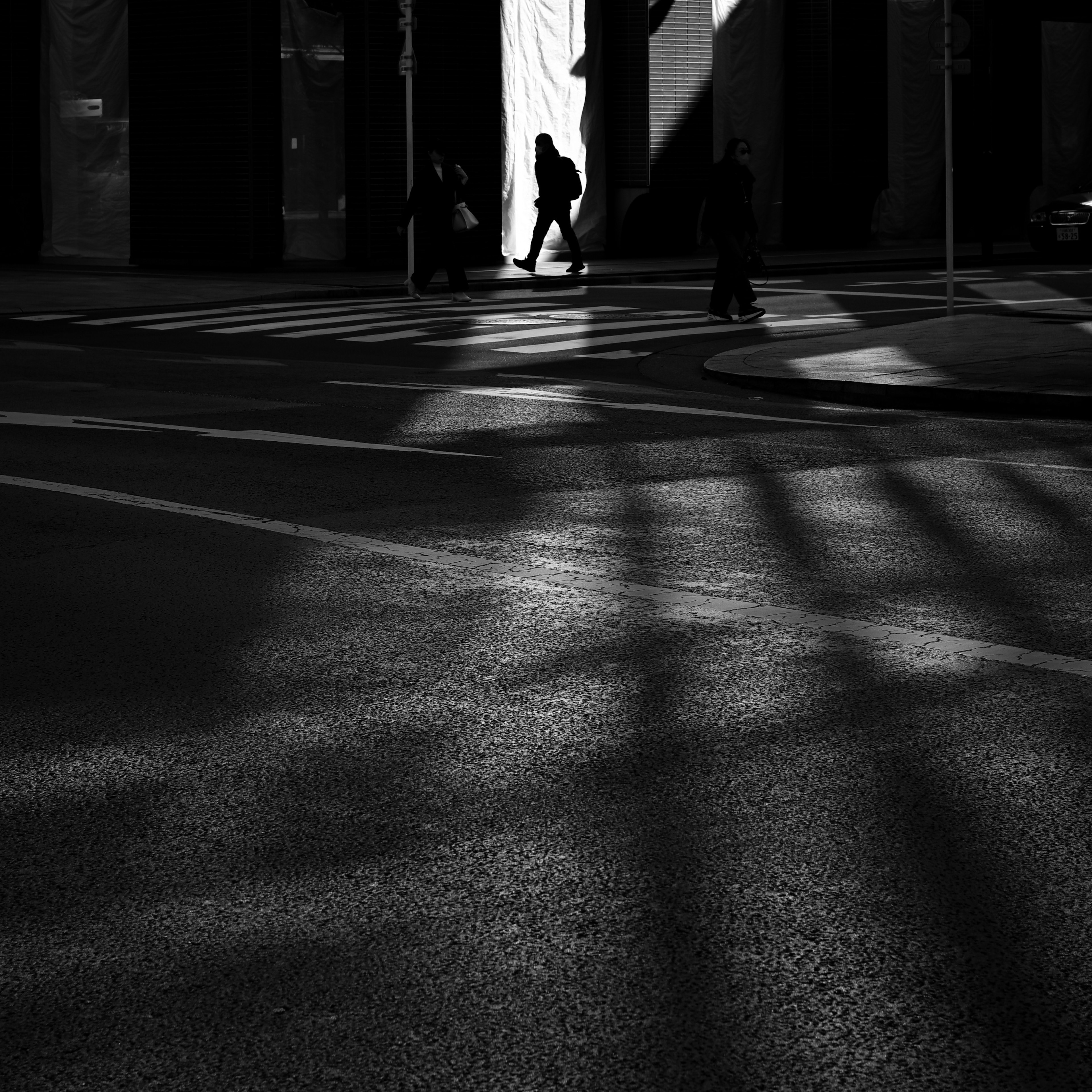 Silhouette of a person walking on a city street with intersecting shadows